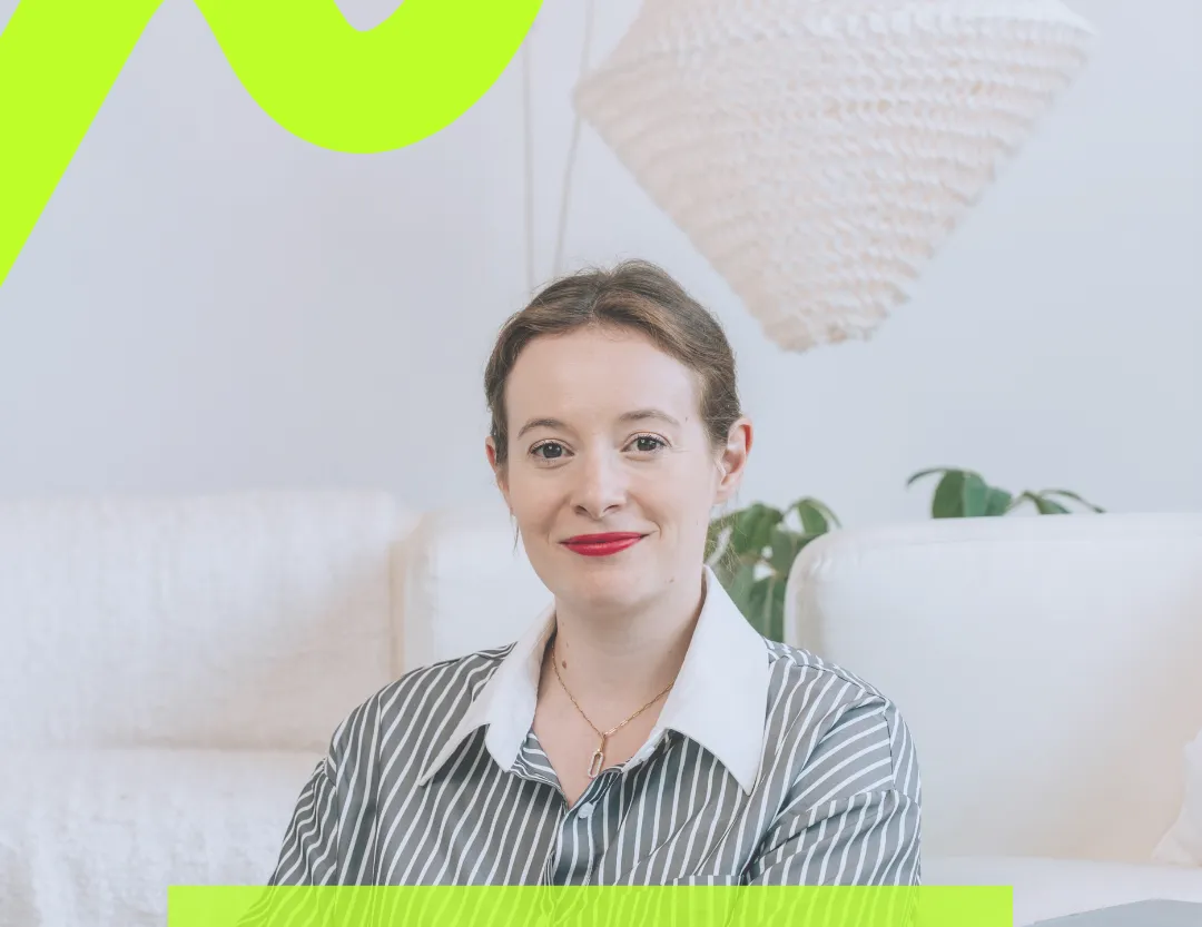 Smiling woman with brown hair wearing a striped shirt sitting in a modern living room.