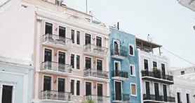 Foto de dos edificios, uno color rosa y otro azul.