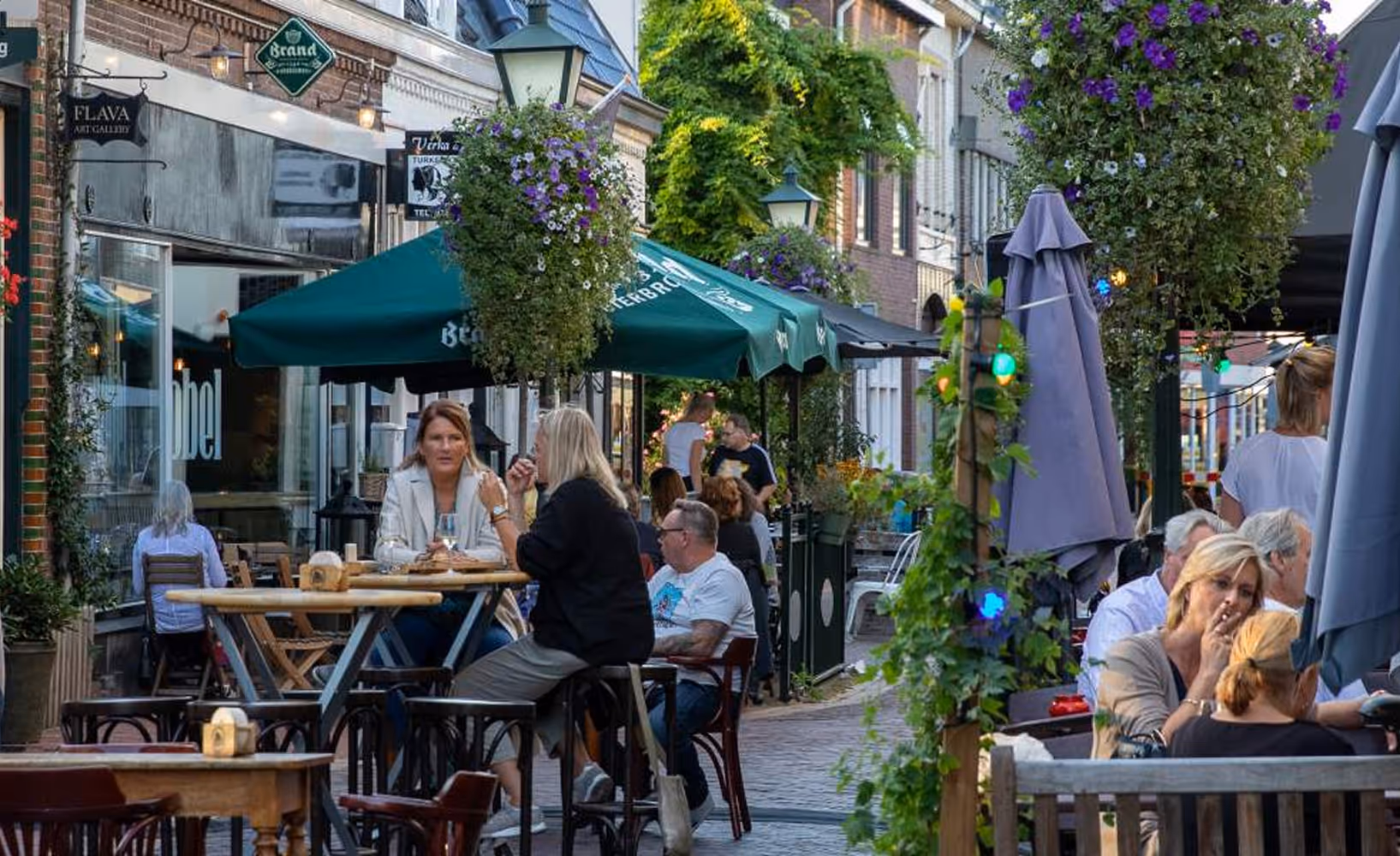 Sfeervolle winkelstraat met terrassen en hangbloemen in Bussum.