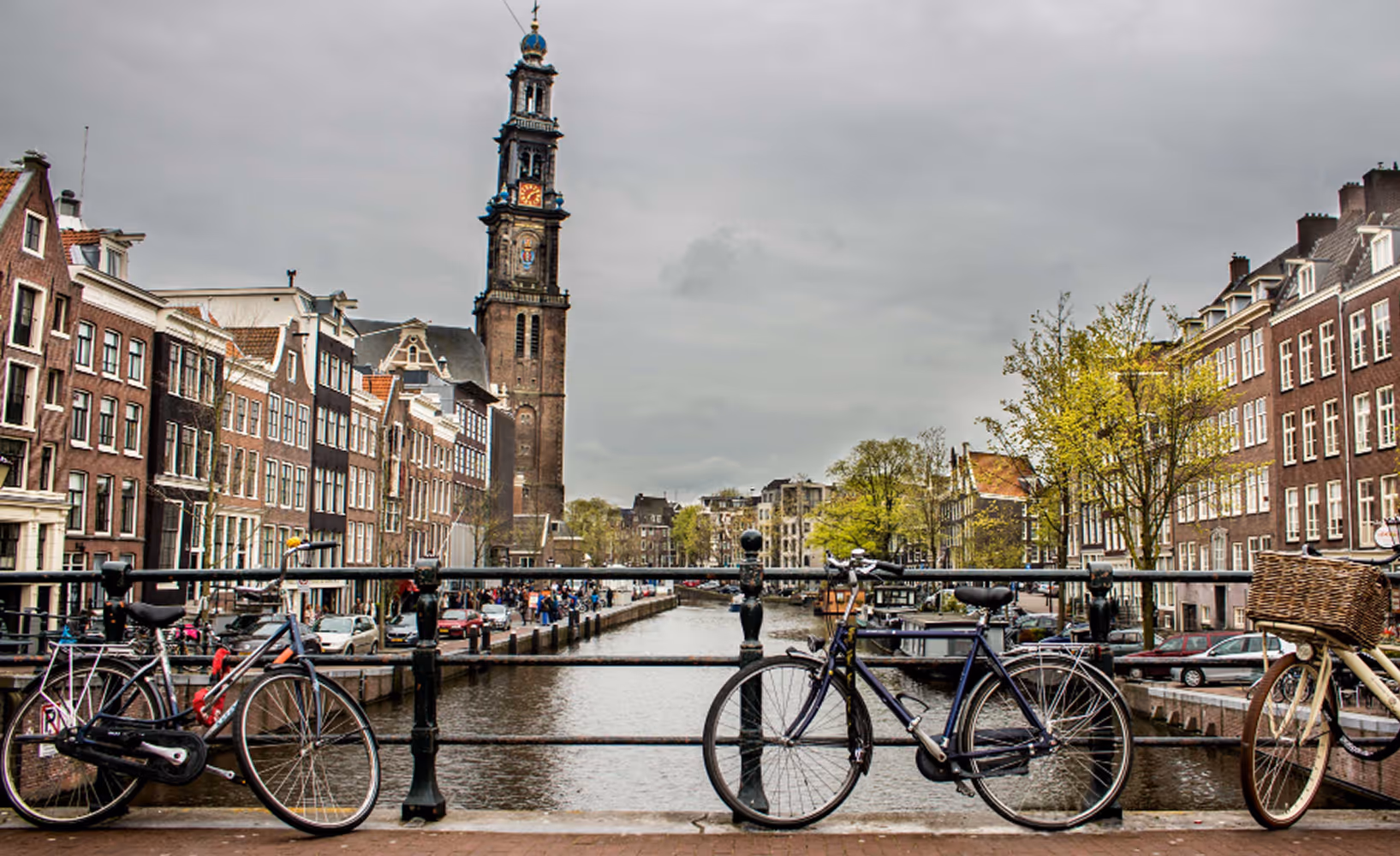 Amsterdamse gracht met fietsen op de brug en de Westerkerk op de achtergrond.