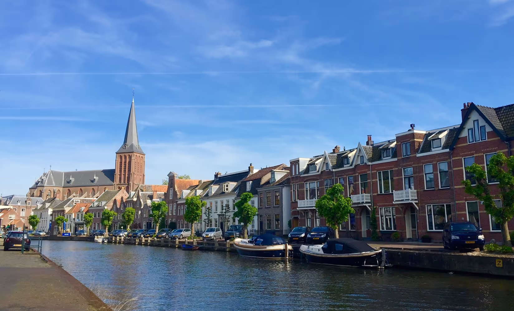 Gracht met woonhuizen, boten en kerk in het historische centrum van Maarssen.