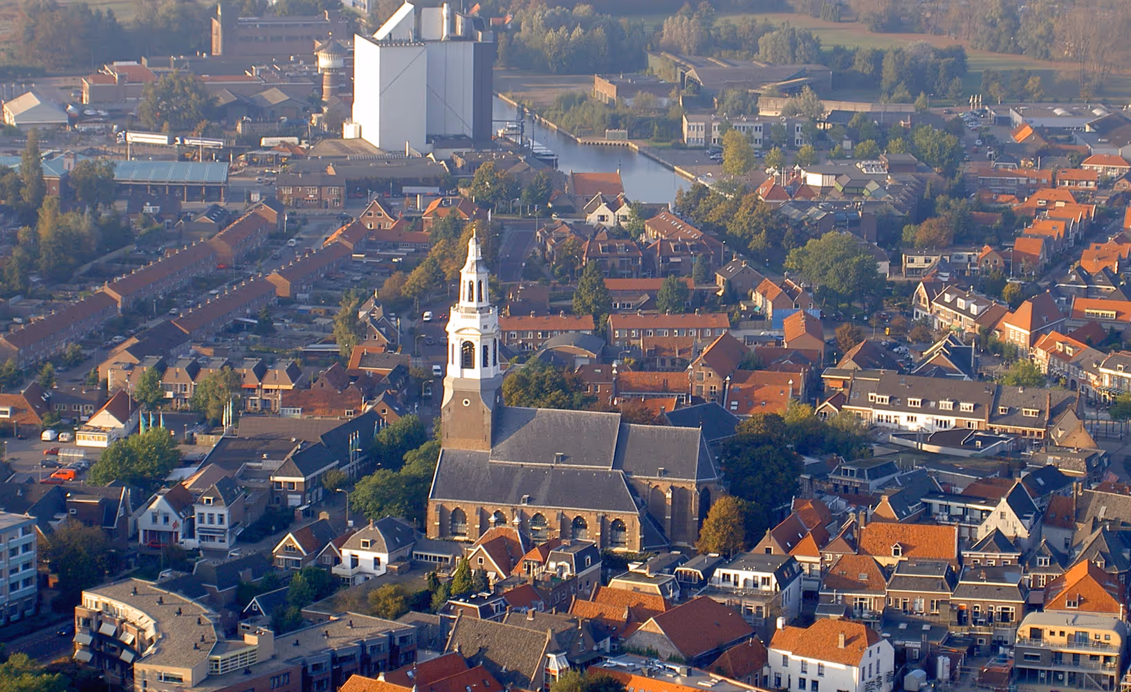 Luchtfoto van Nijkerk met kerk, woonwijken en industrieterrein op de achtergrond.
