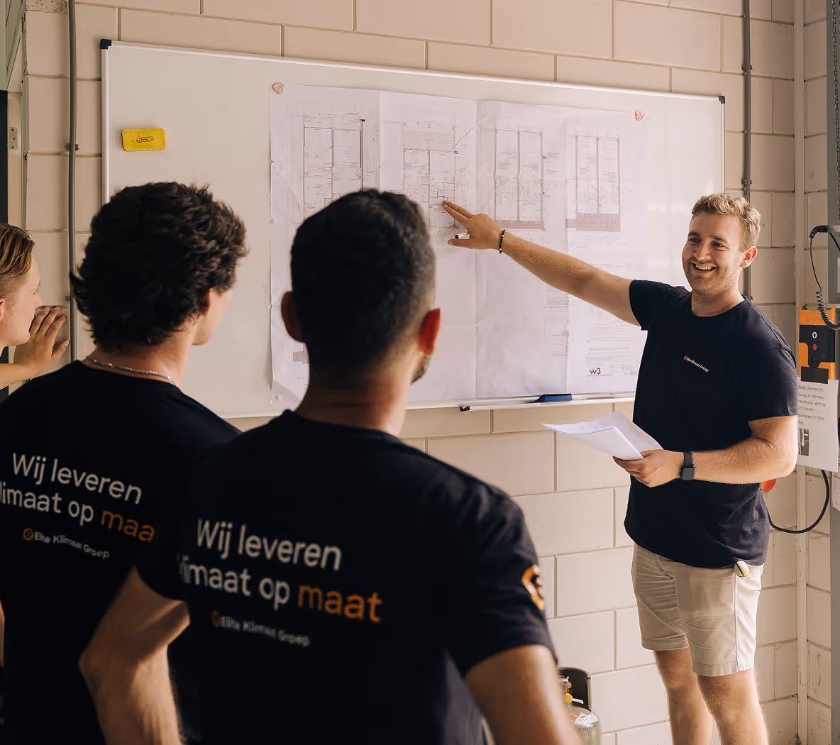 Medewerkers van Elite Klimaat Groep bespreken technische tekeningen tijdens een werkoverleg.