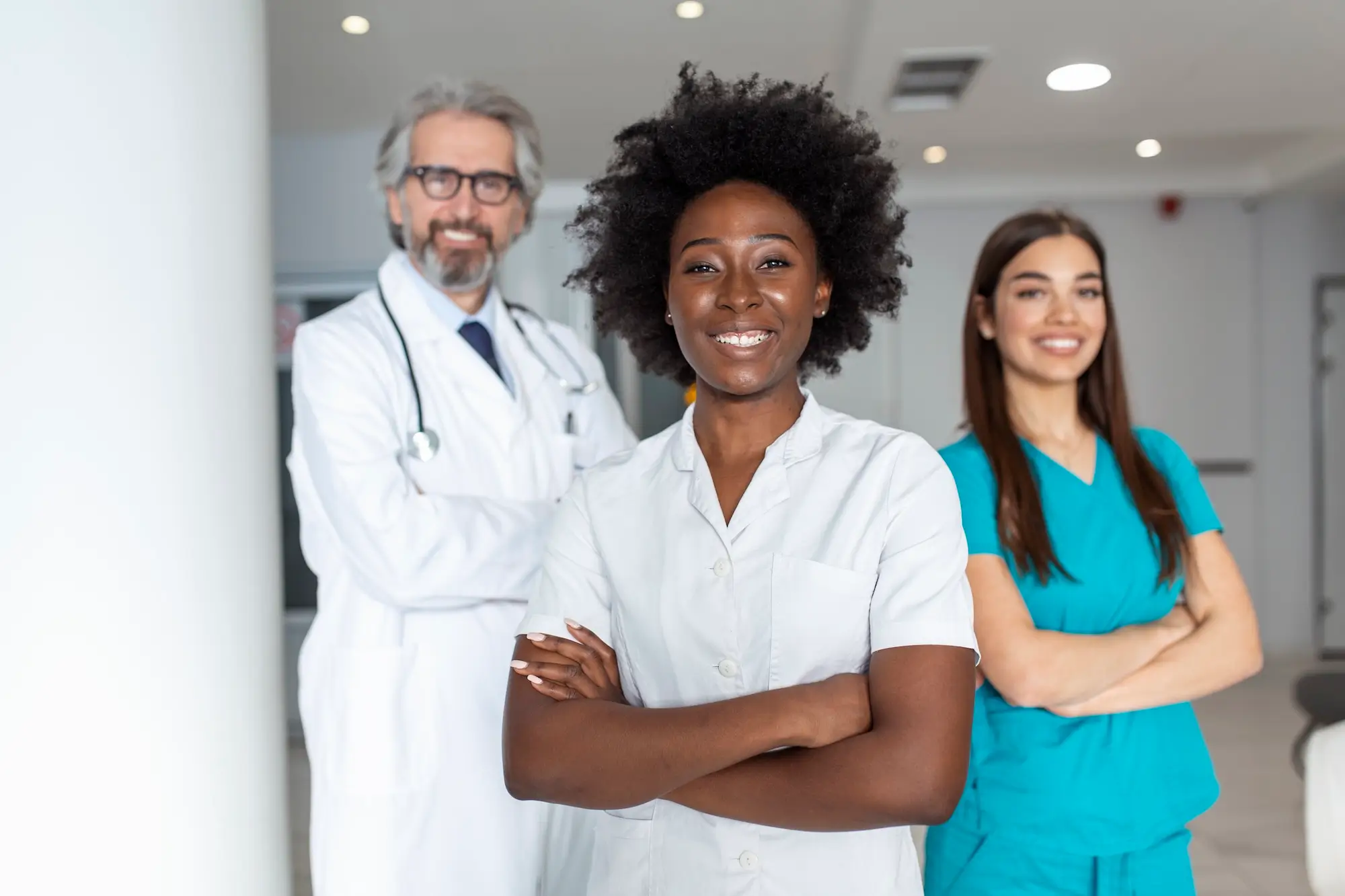 three-doctors-nurses-standing-hospital-wearing-scrubs-smiling