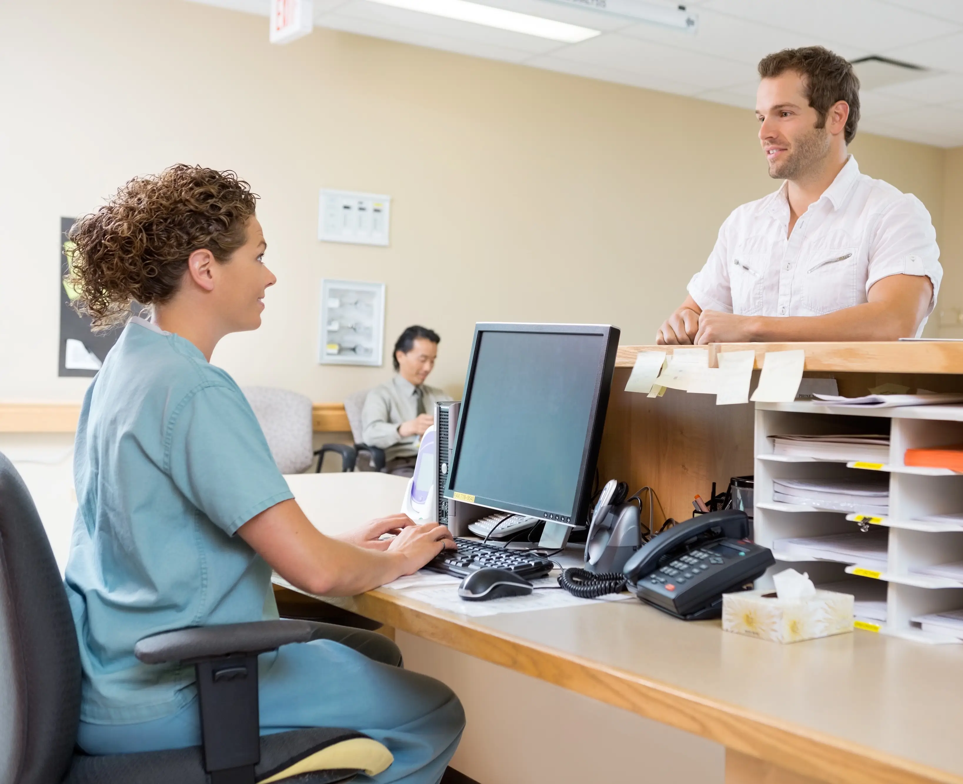 A nurse converses with a patient at a desk, providing care and support in a healthcare setting.