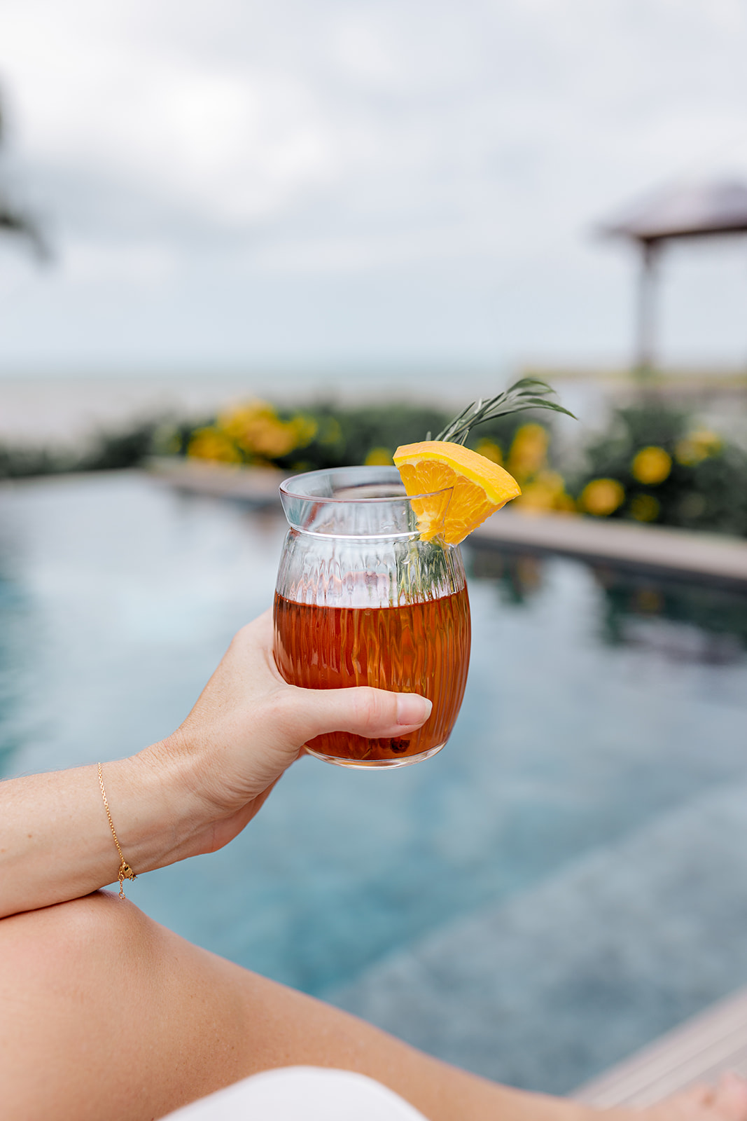 Verre d’infusion Cacaothé glacée à l’orange et au romarin face à la piscine