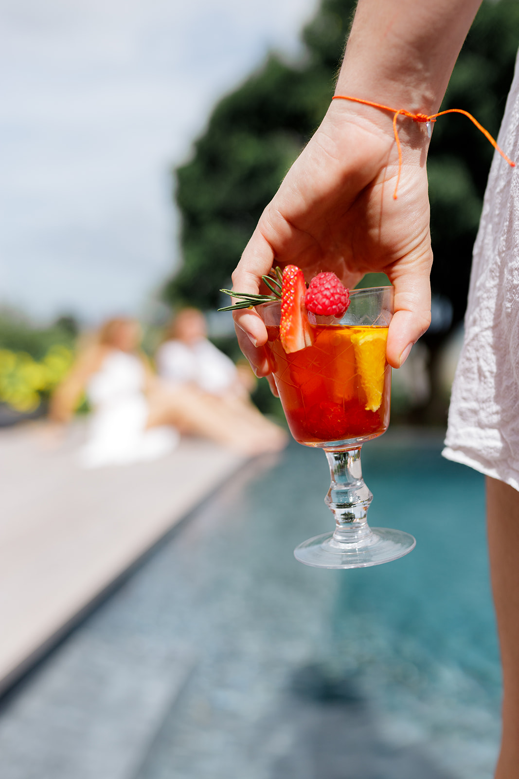 Verre à pied de sangria sans alcool au cacao, orange et fruits rouges au bord de la piscine