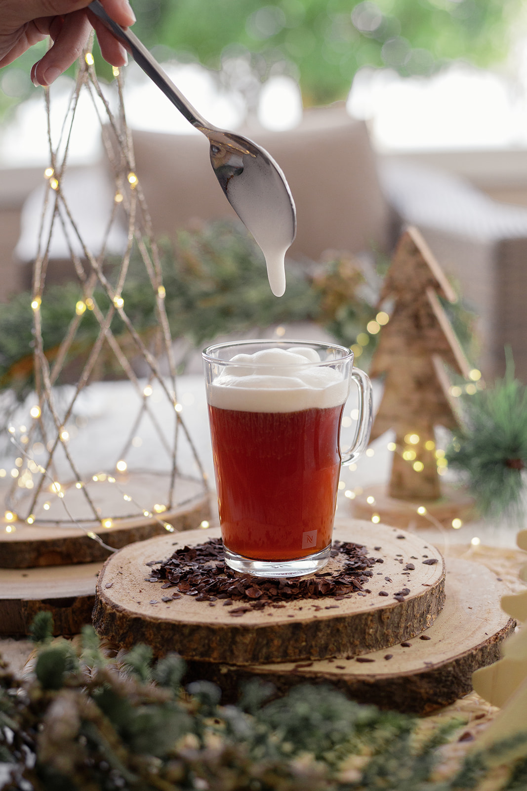 Mousse de lait déposée à la cuillère sur une infusion de cacao, décor de Noël