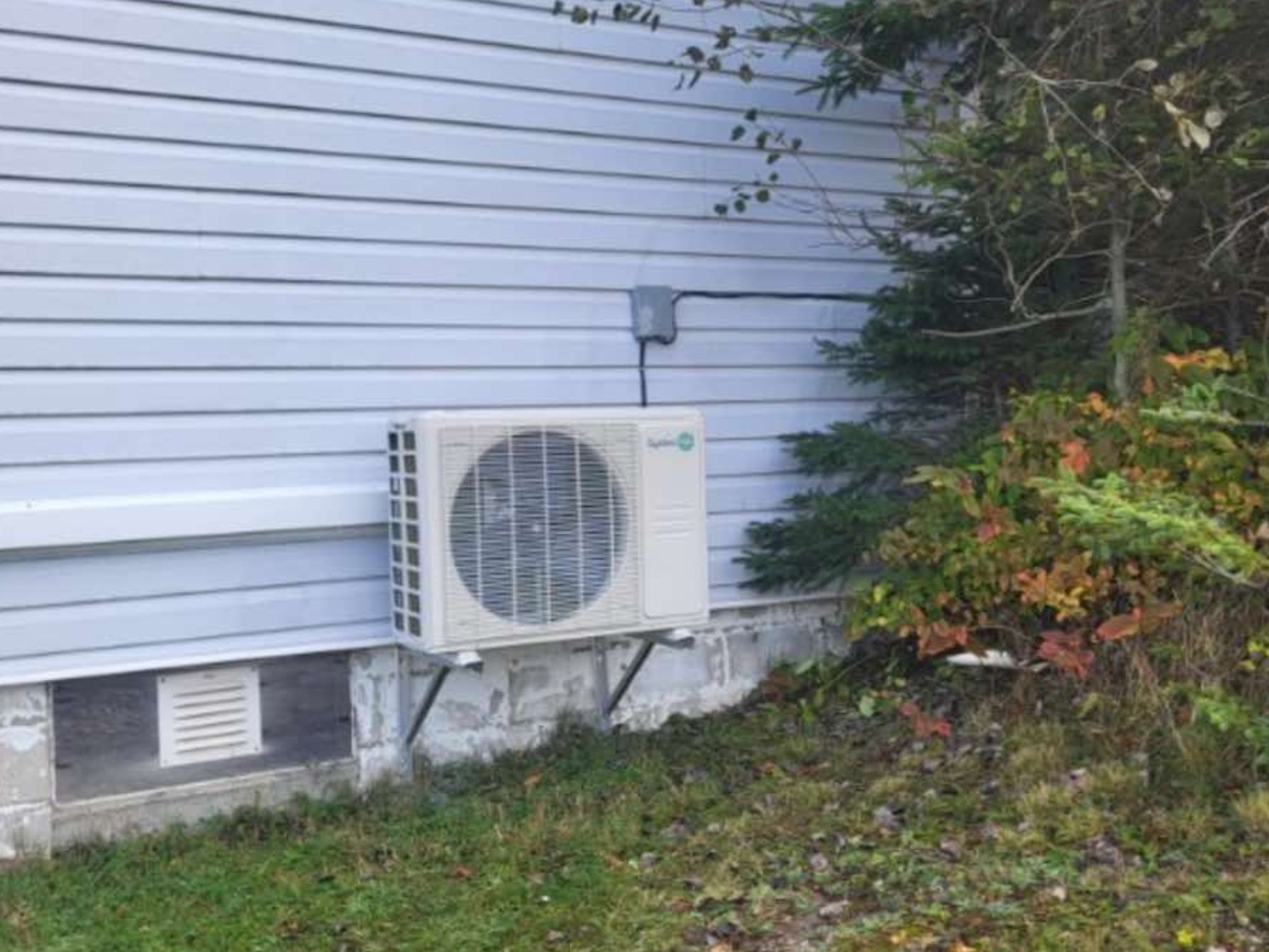 compresseur de thermopompe sur le mur d'une maison
