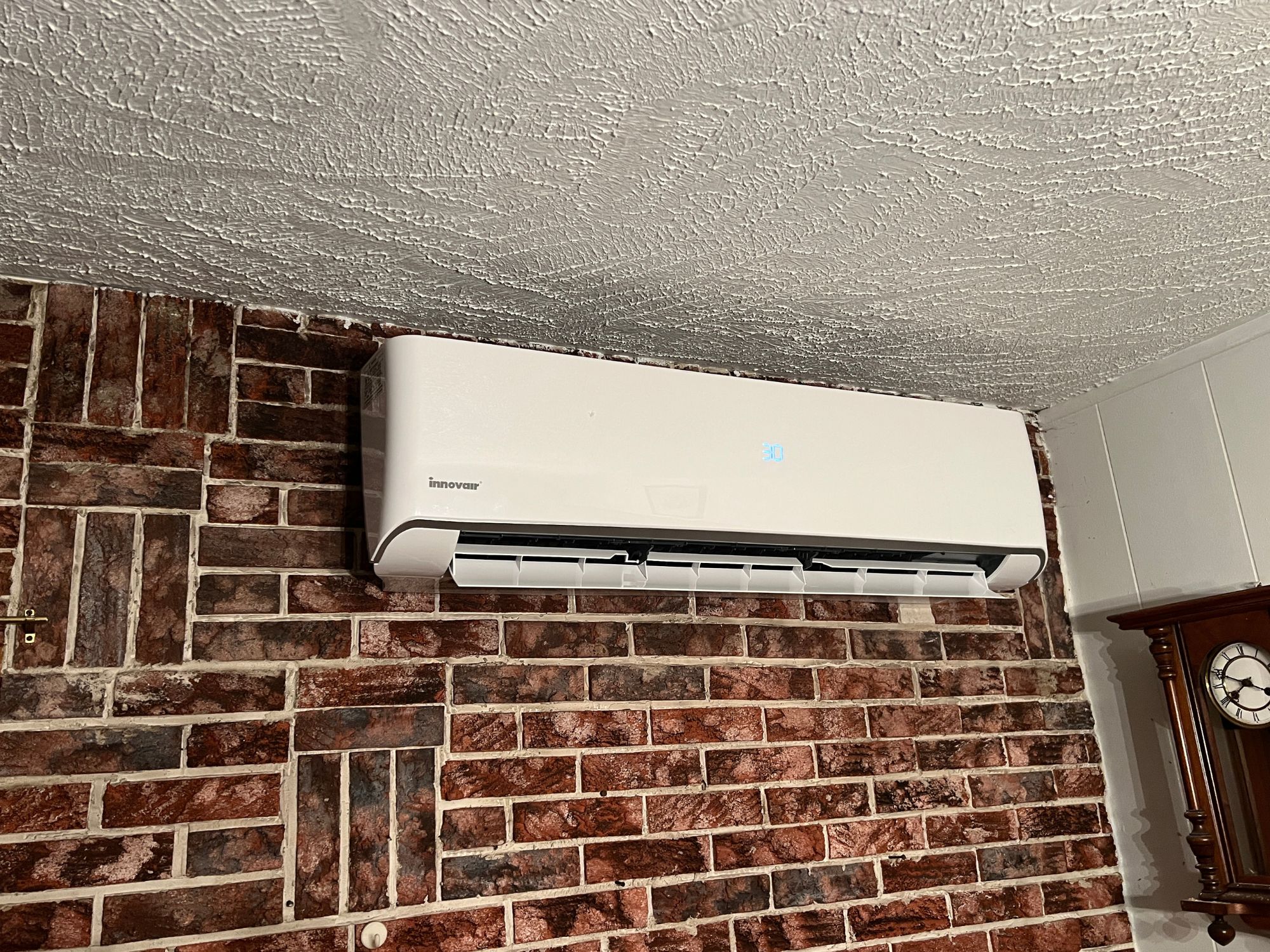 Thermopompe installée sur un mur de salon en brique