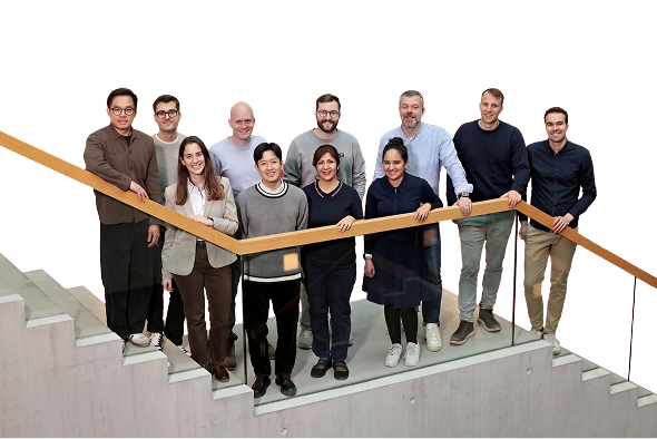 A group of ten diverse adults standing on stairs with wooden railing, smiling at the camera.