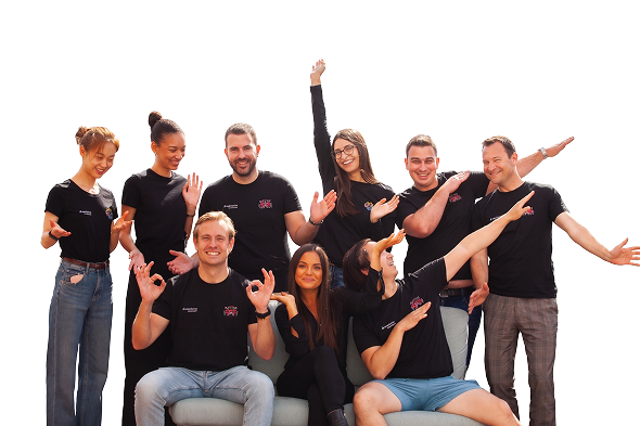 Group of nine young adults in black shirts posing happily with various hand gestures and smiles.