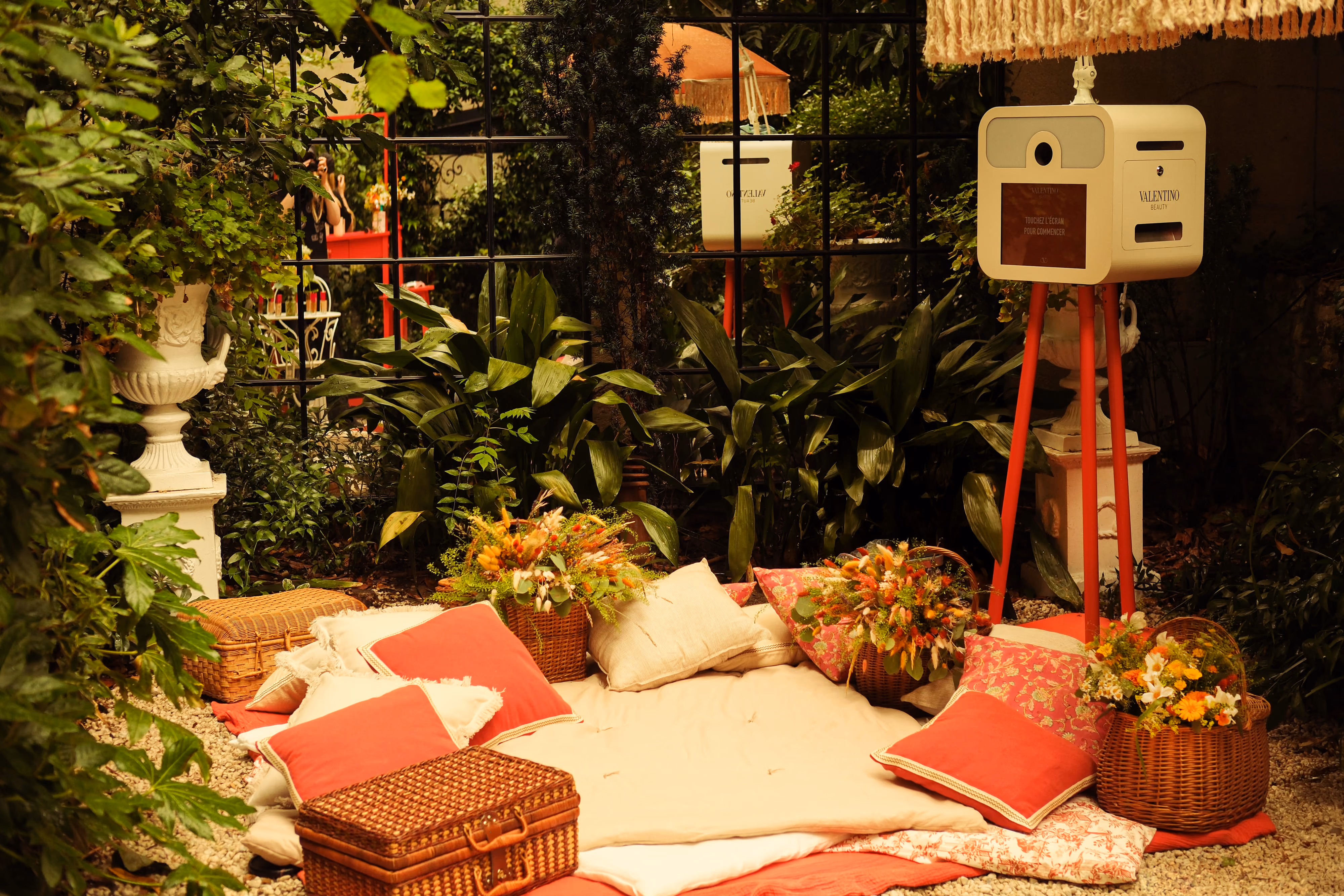 Décor de shooting en extérieur : coussins, tapis et enceinte vintage installés dans un jardin