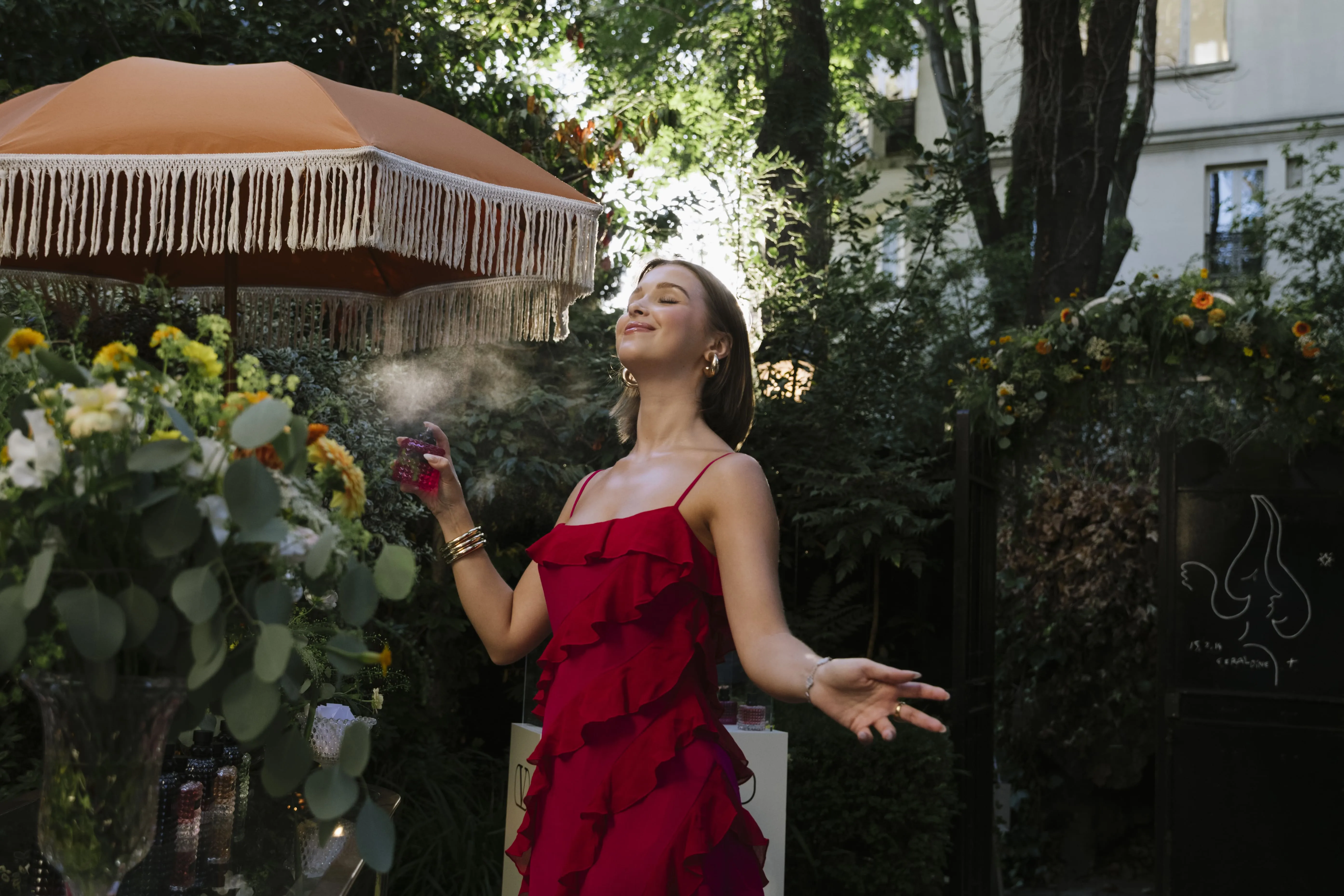 Comédienne en robe rouge dans un décor d'activation de marque sous une structure végétalisée