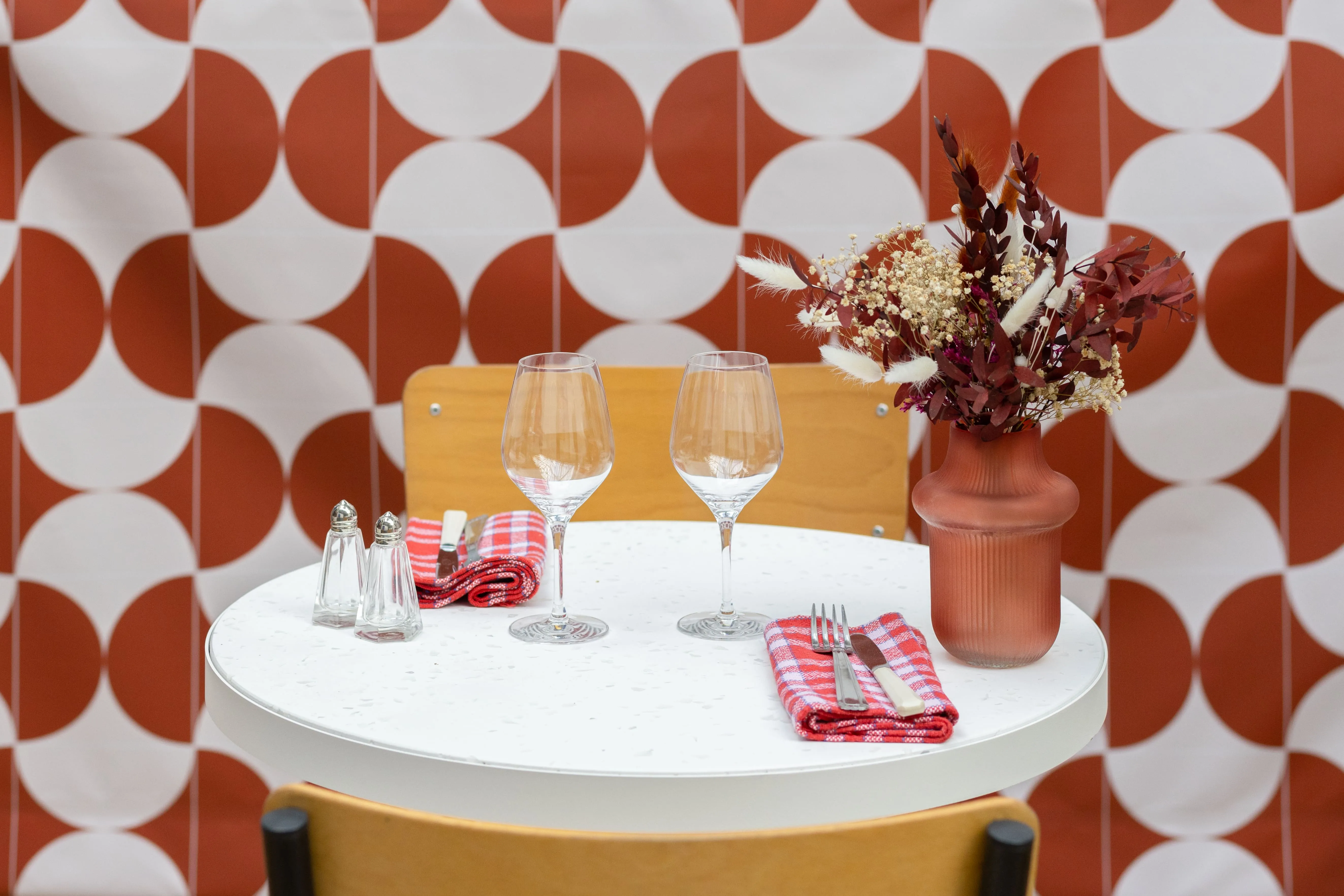 Table dressée devant un mur à motifs géométriques terracotta dans un bar