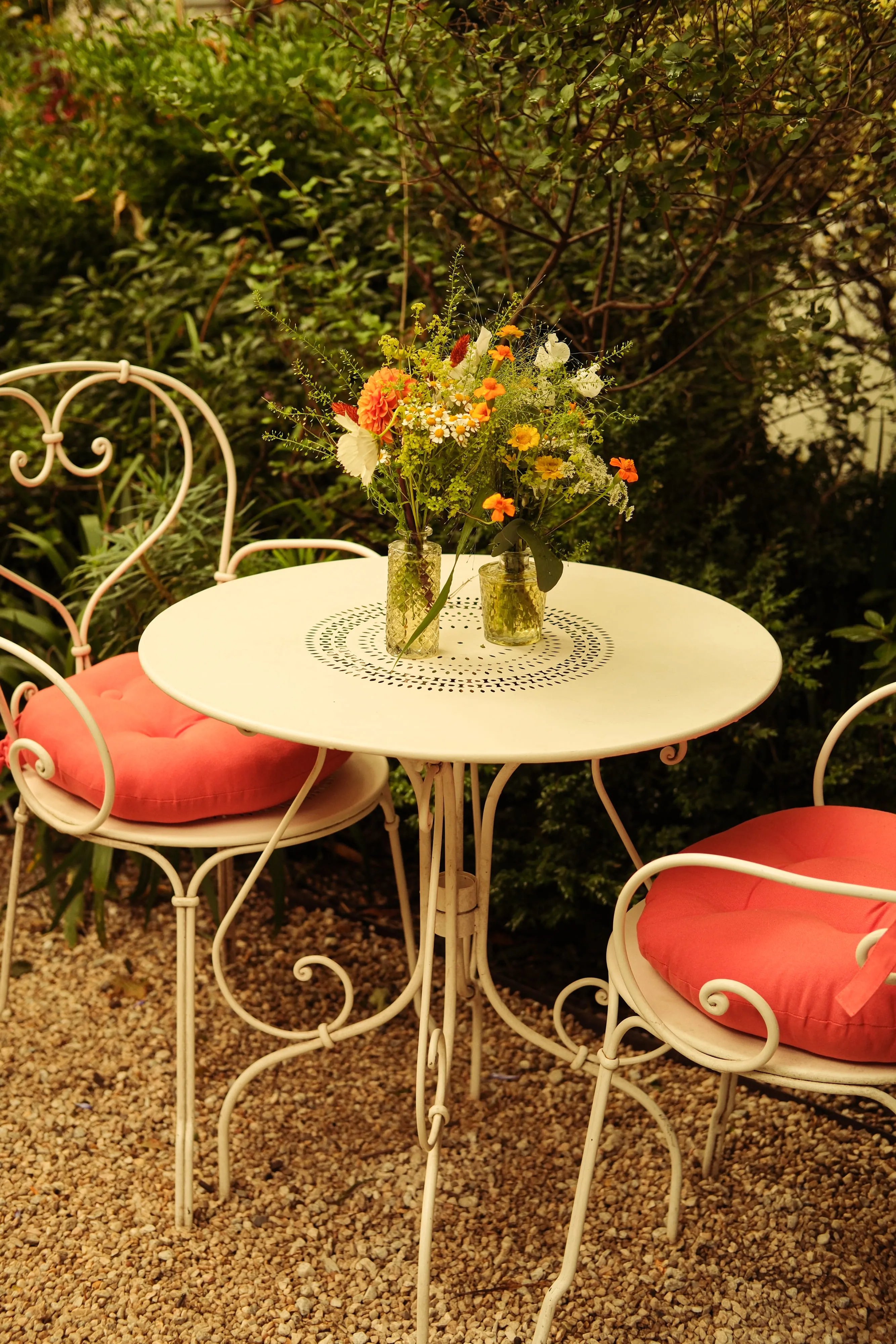 Terrasse de restaurant : table ronde jaune, chaises en fer forgé et bouquet de fleurs