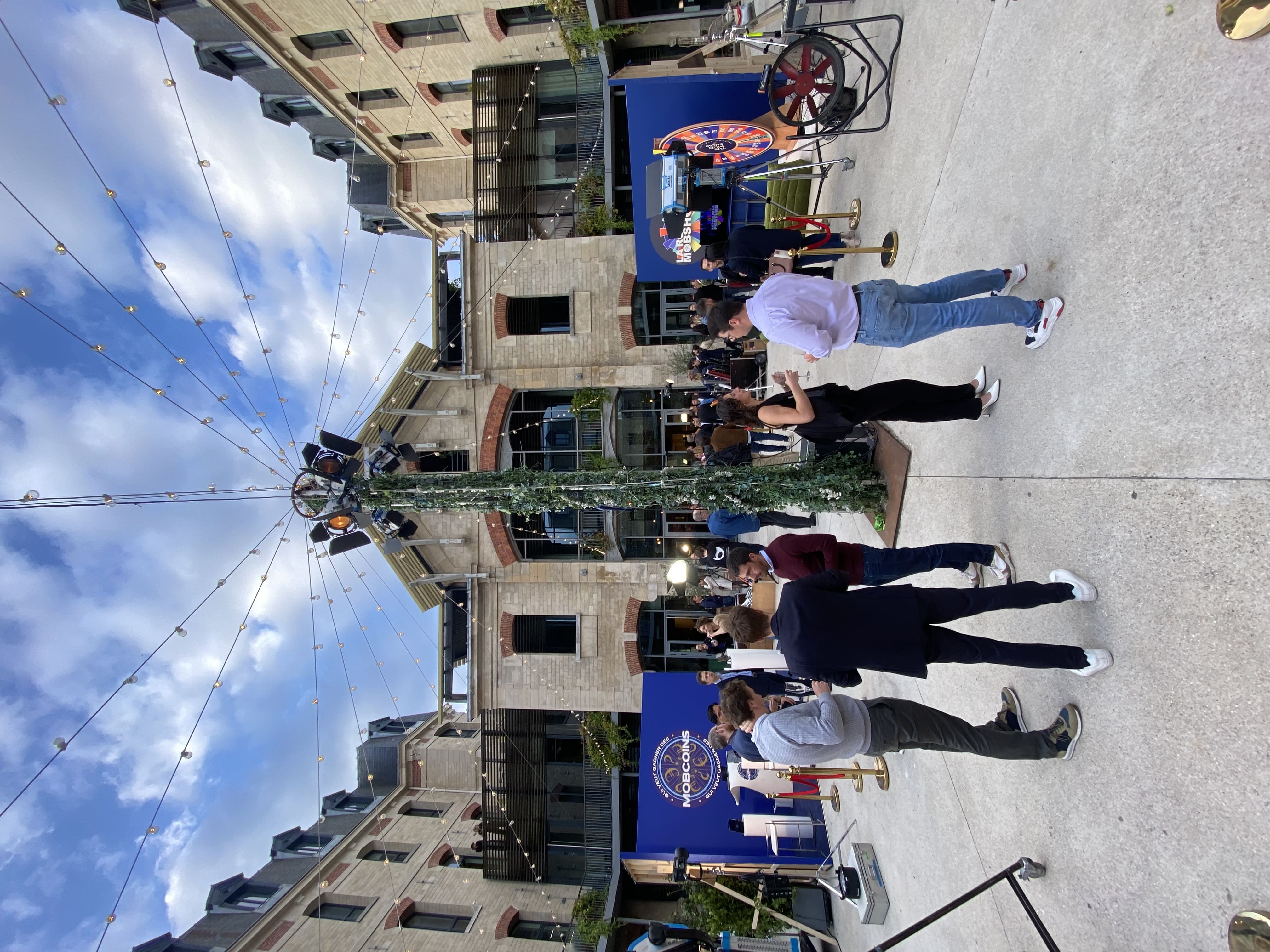 Invités qui boivent et parlent dans la cour de la Caserne autour d'un poteau central