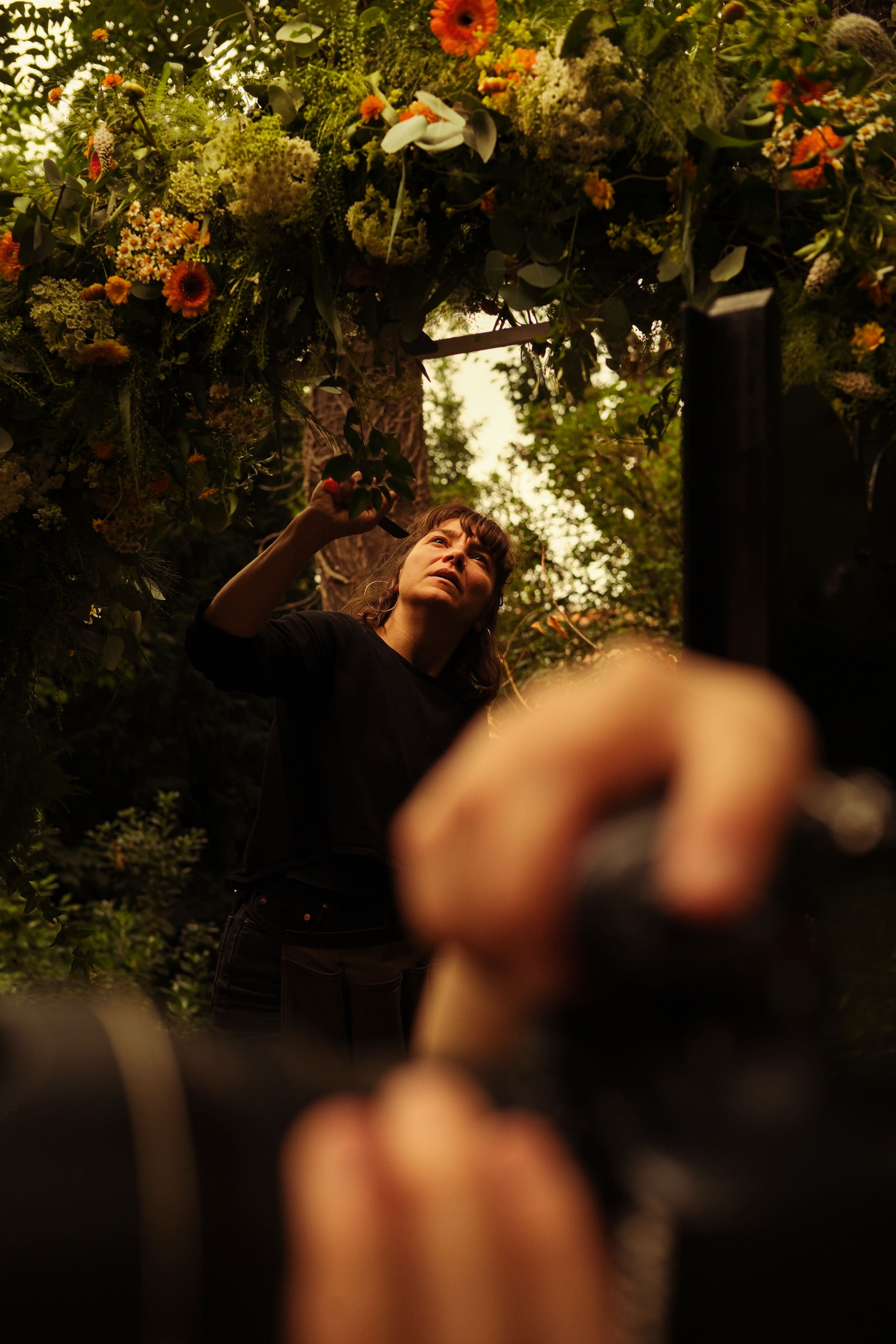 monteuse et partenaire qui crée une arche de fleurs oranges, blanches et vertes