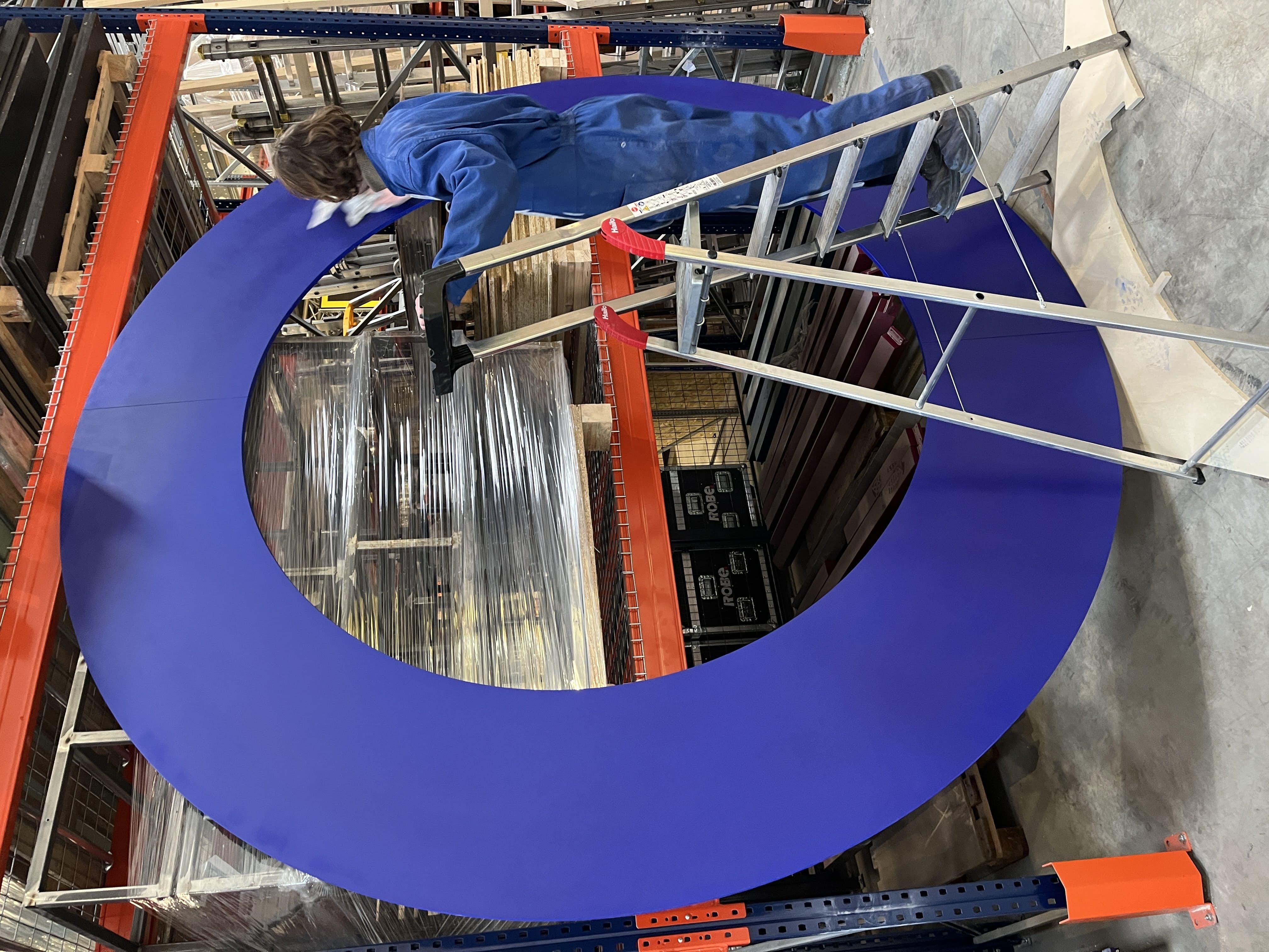 ouvrier sur échelle, peinture bleue, structure en bois