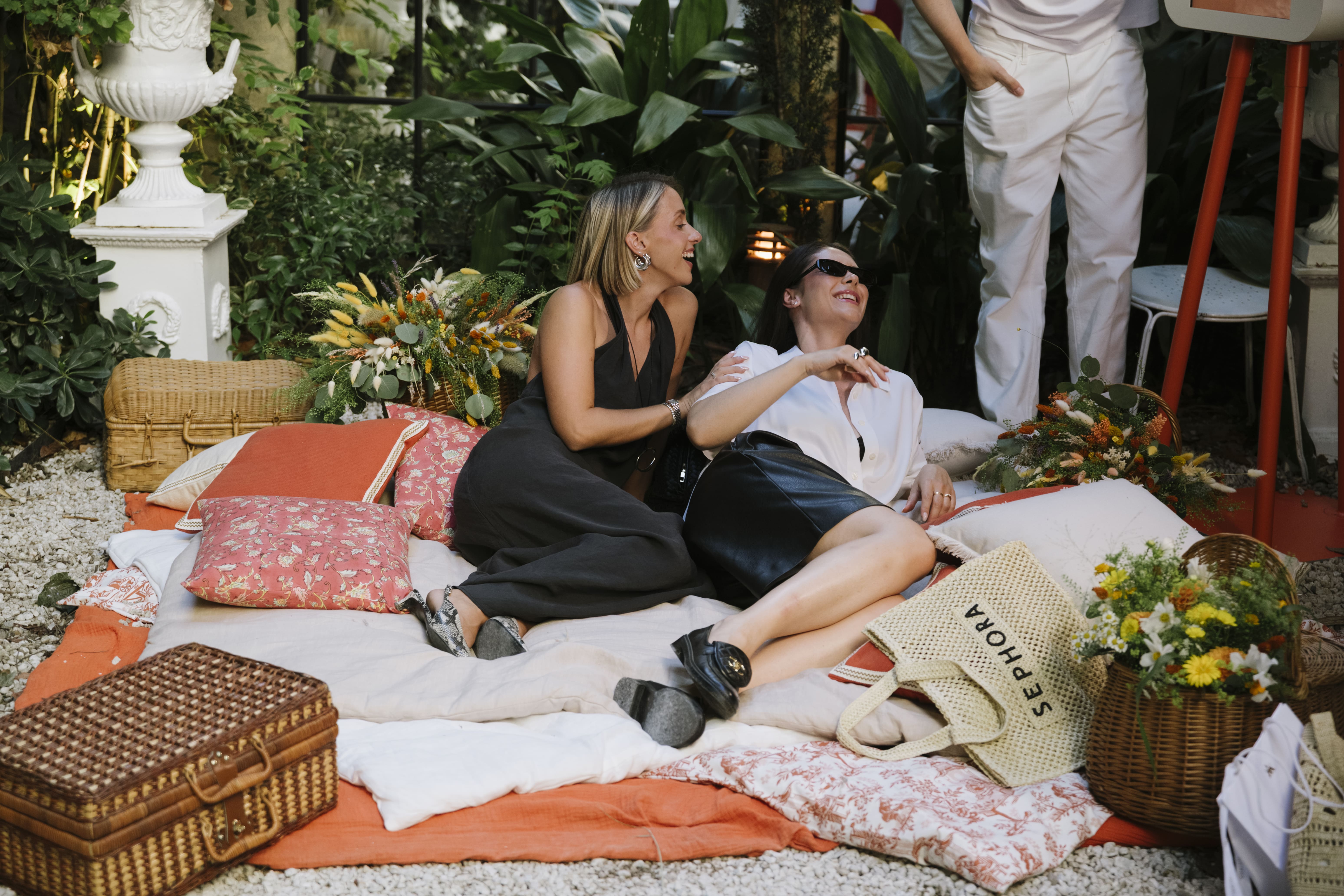 Femmes alongées sur coussins oranges et fleuris, amphore fleurie, paniers en osier, fleurs séchées, toile, photocall