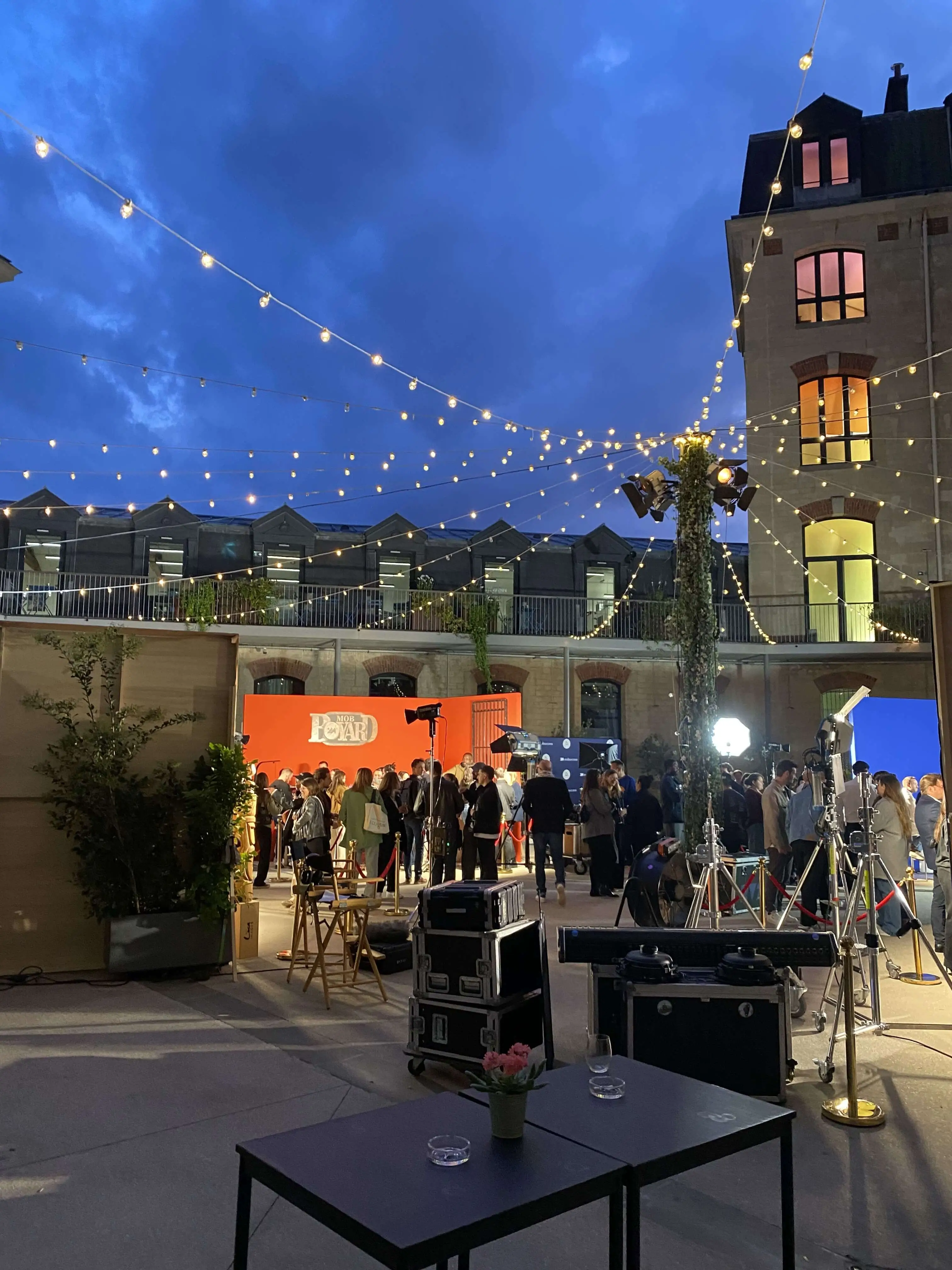 tables, malettes, immeubles, guirlandes de guinguettes autour des poteaux, spots, chaises de cinéma, barrières de cinéma