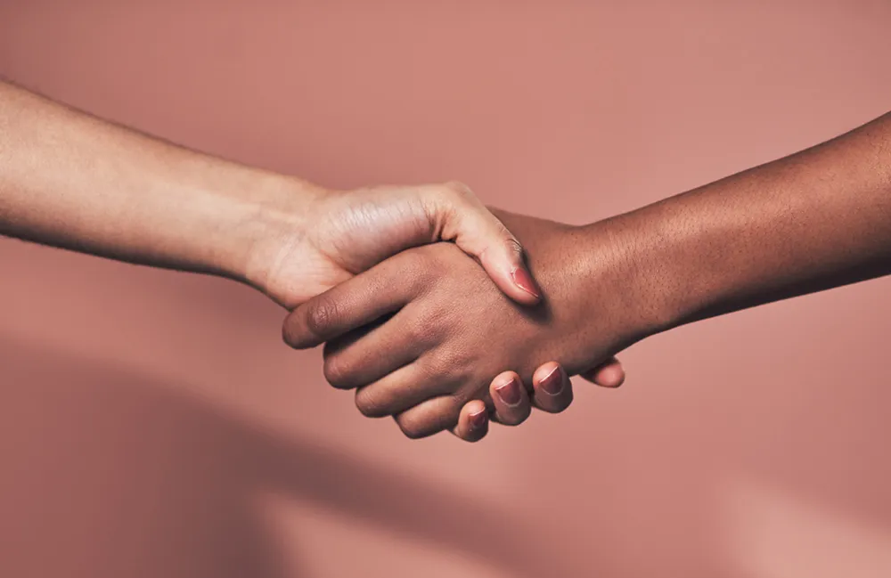 Two people shaking hands against a pink background