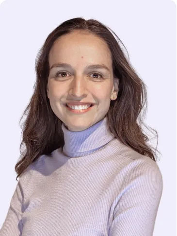 Portrait of Lora, smiling, wearing a lilac turtleneck