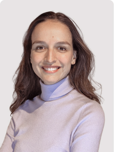 Portrait of Lora, smiling, wearing a lilac turtleneck