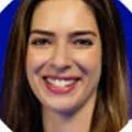Close-up of a smiling woman with long brown hair against a blue background.