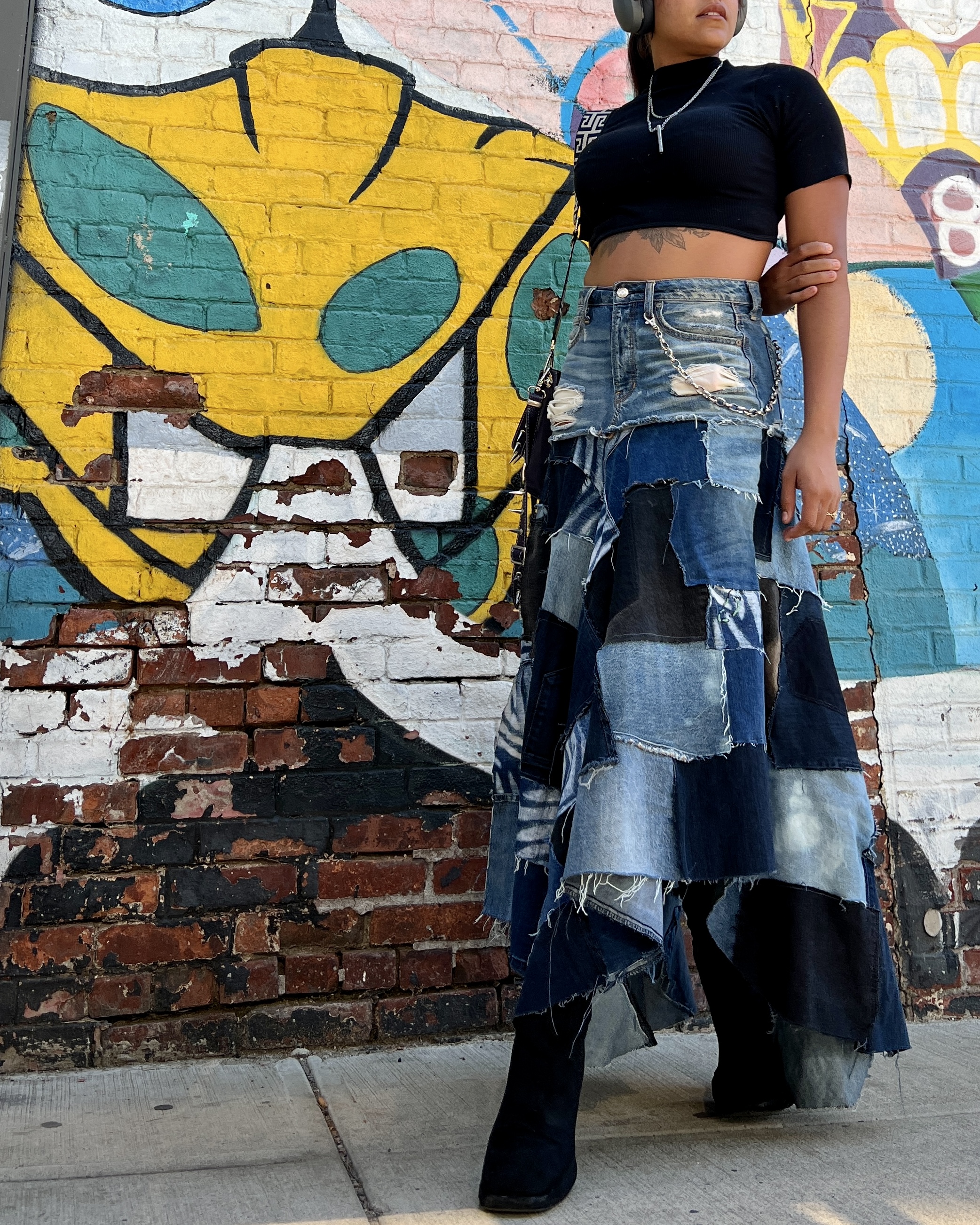aaliyah wearing her ankle lank handkerchief style denim patchwork skirt in front of a graffitied wall