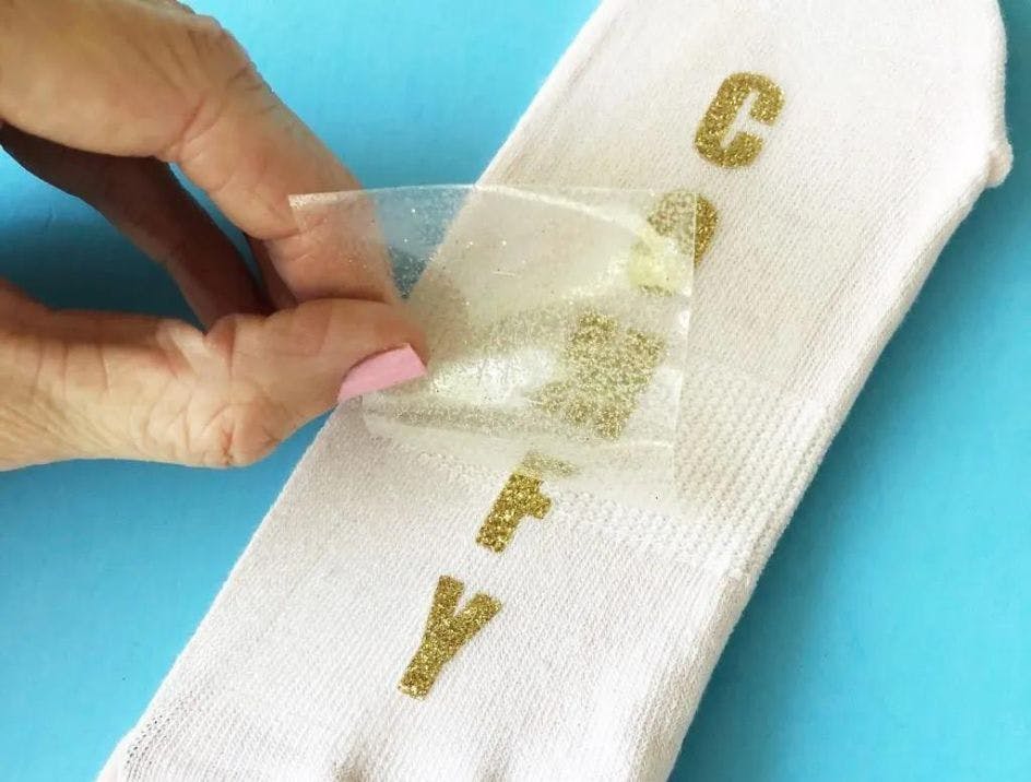 Custom socks showing the process of heat transferring a design onto a pair of white socks