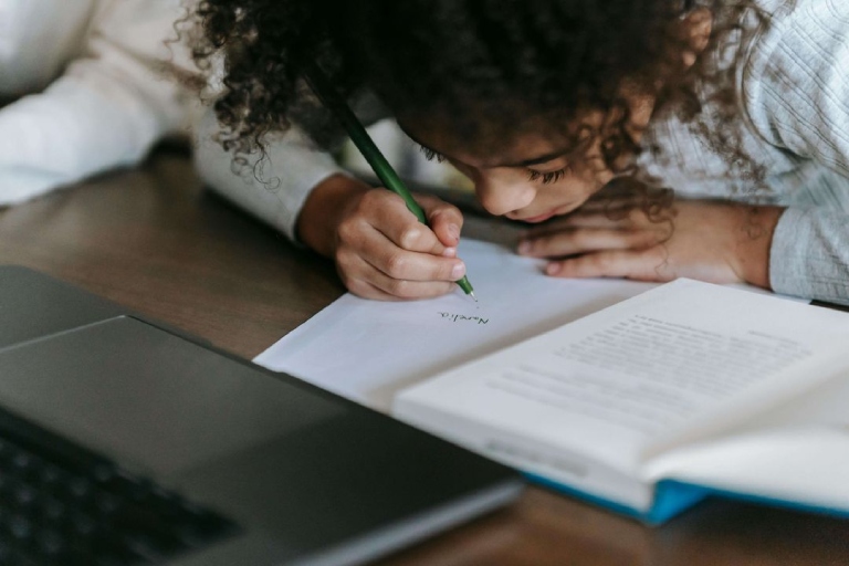 Child writing with their face very close to the page