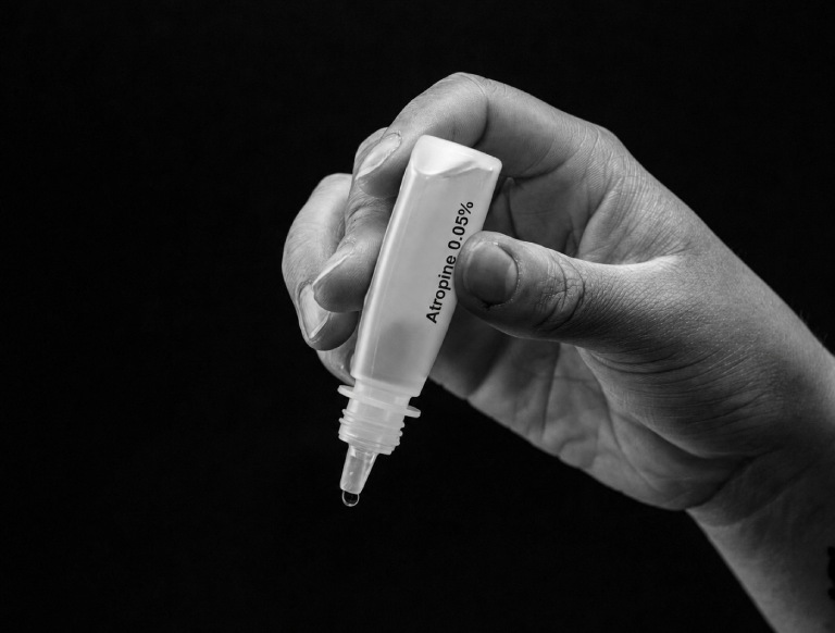 Hand holding a bottle of atropine 0.05% eye drops used for childhood myopia control