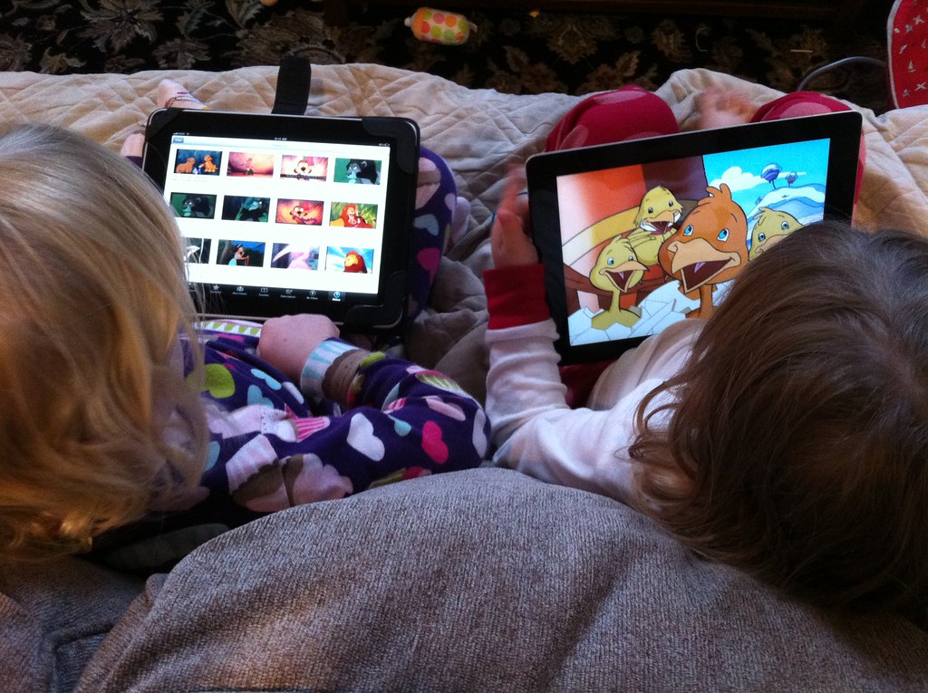 Two young children using tablet devices at close range