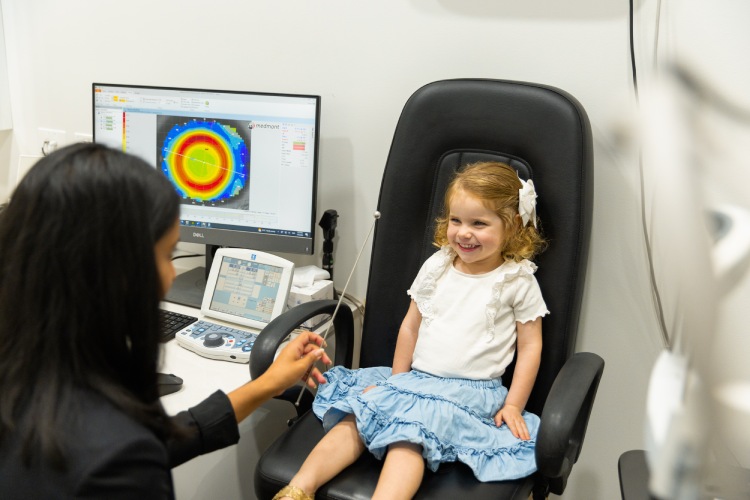 Young child smiling during an eye test with an optometrist in Adelaide