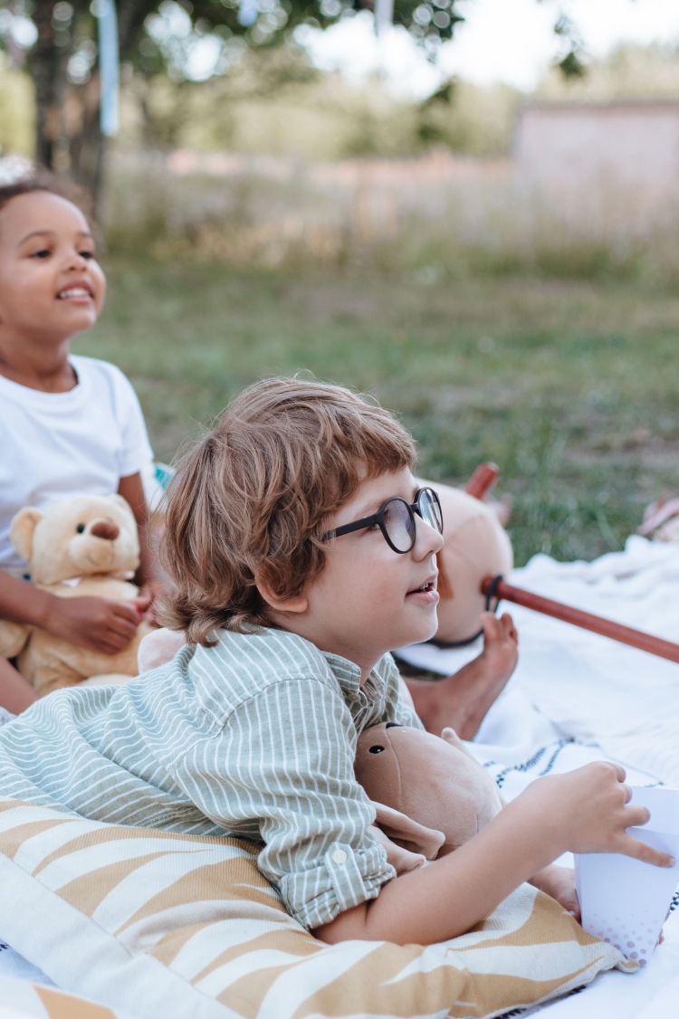 Young child wearing glasses outdoors with friends