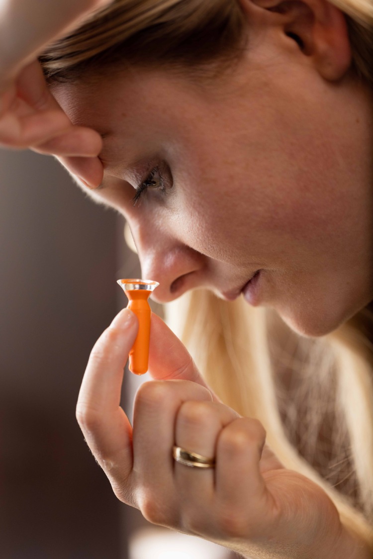 Person preparing to insert a scleral contact lens using an orange insertion plunger