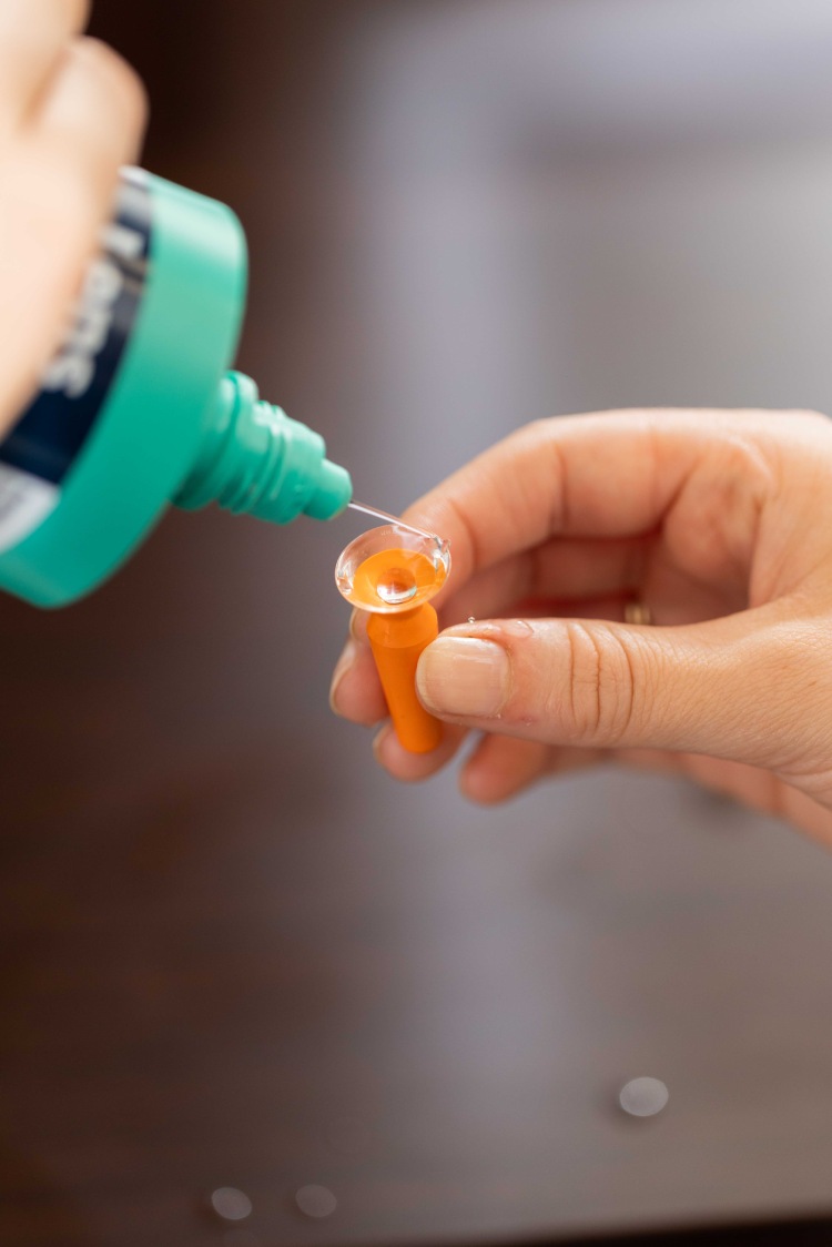 Scleral contact lens being rinsed with solution while held on an insertion plunger