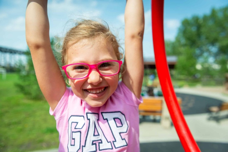 Young child wearing glasses and playing outdoors