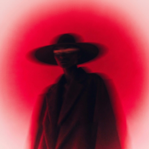 Blurred photo of a figure in a wide-brimmed hat against a red glow, made with Recraft