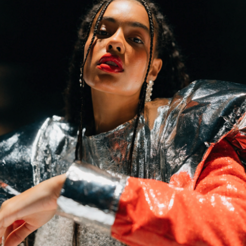 Fashion photo of a woman in a silver jacket with red sleeves and red lipstick, made with Recraft