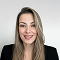 Smiling woman with long blonde hair wearing a black blazer against a plain light background.