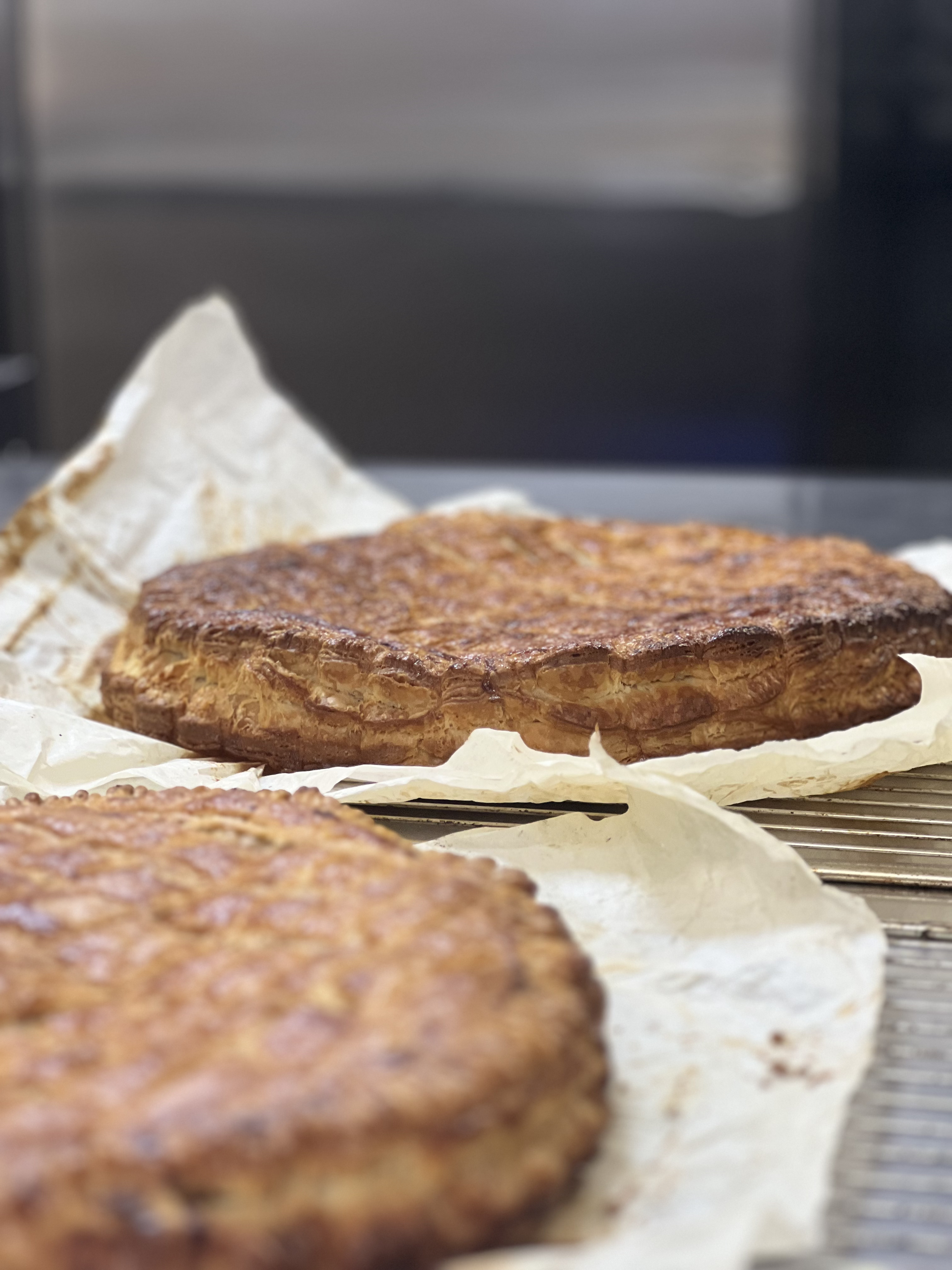 Deux pâtisseries rondes, dorées à point, reposant sur du papier sulfurisé posé sur une grille métallique.