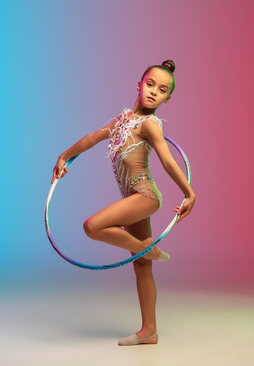A young gymnast with a hula hoop dancing on one leg