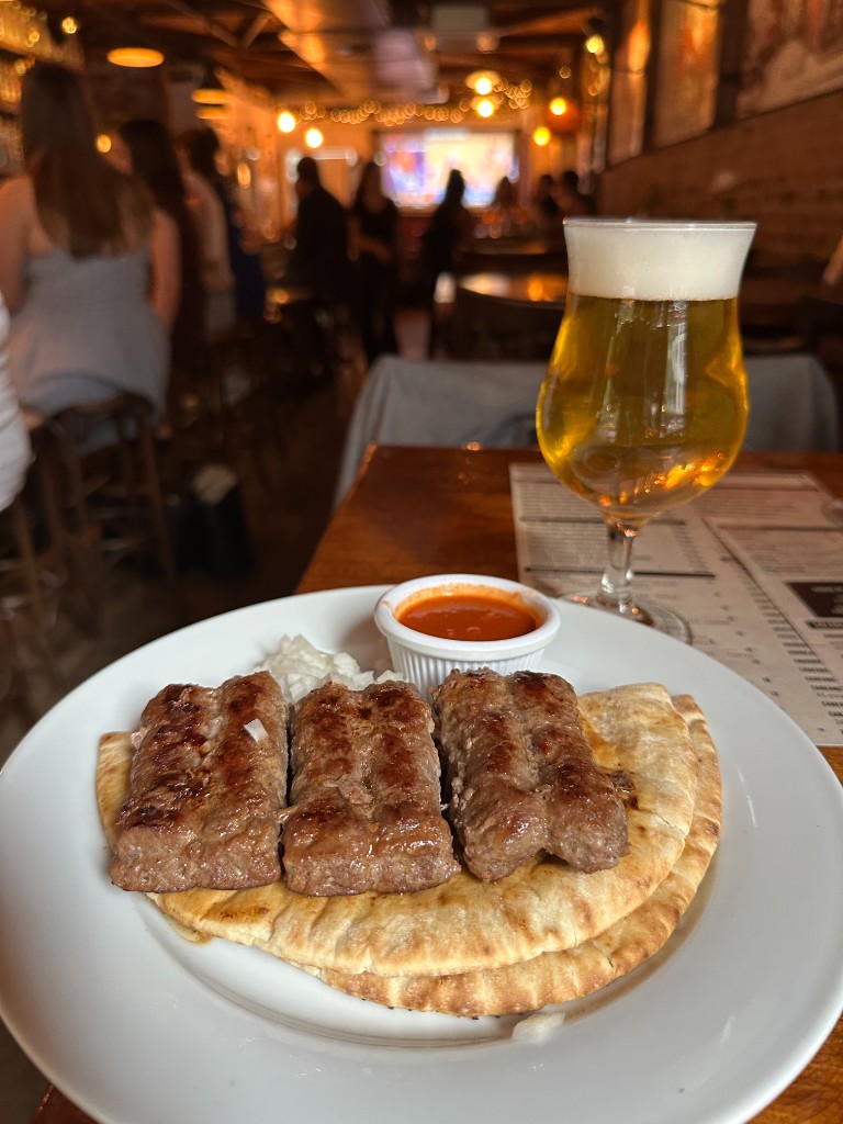 Balkan cevapi grilled beef sausages with ajvar, onions, and bread served with beer at Kurant Wine Bar, World Cup game-day special for $16.