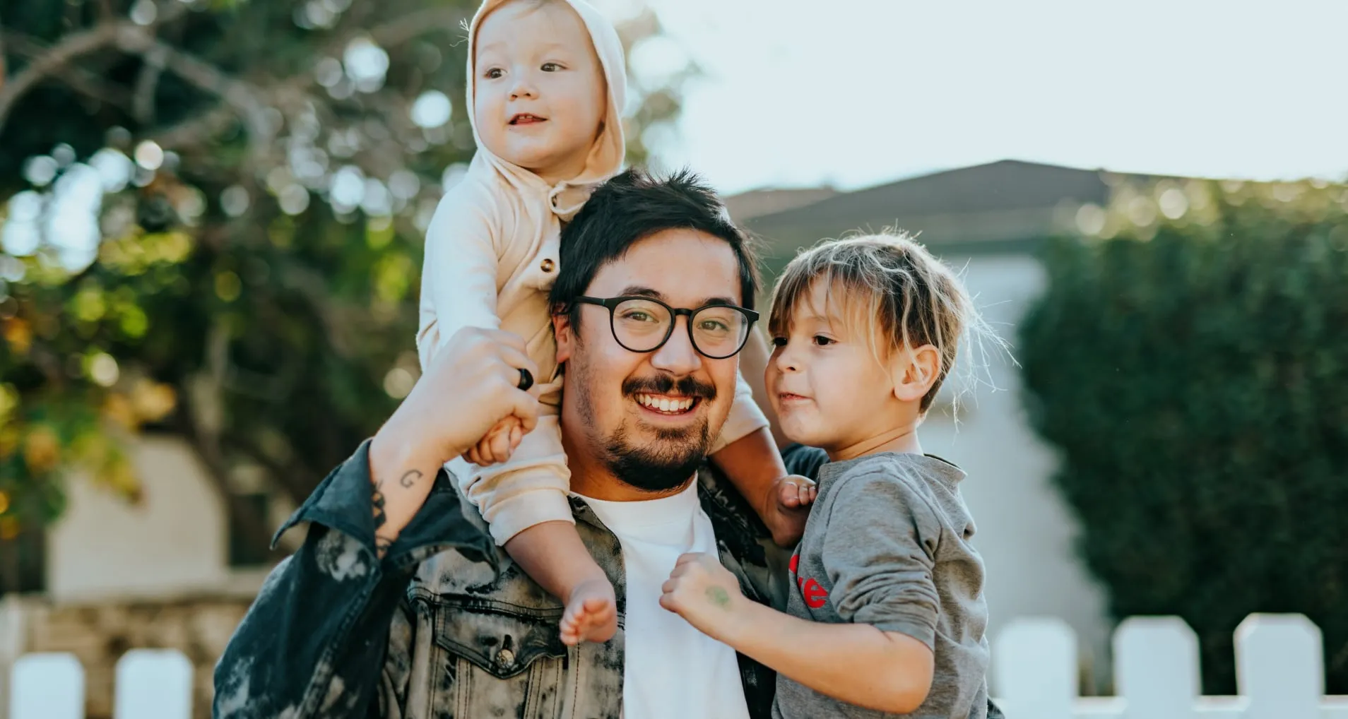 A dad holding his two kids and smiling. 