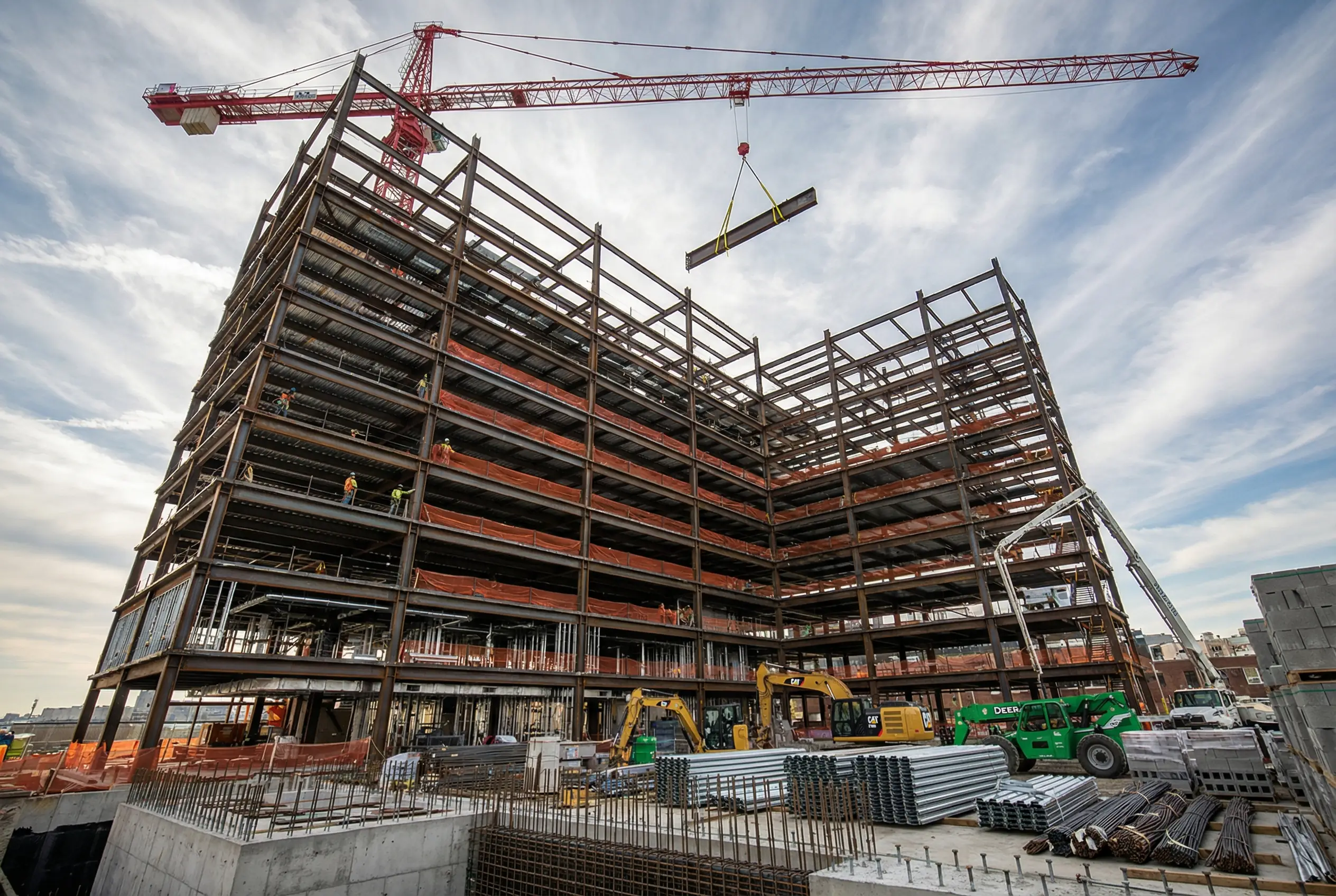 Steel frame construction of vertical manufacturing building at Brooklyn Navy Yard showing tower crane, multiple floor levels, and heavy construction equipment