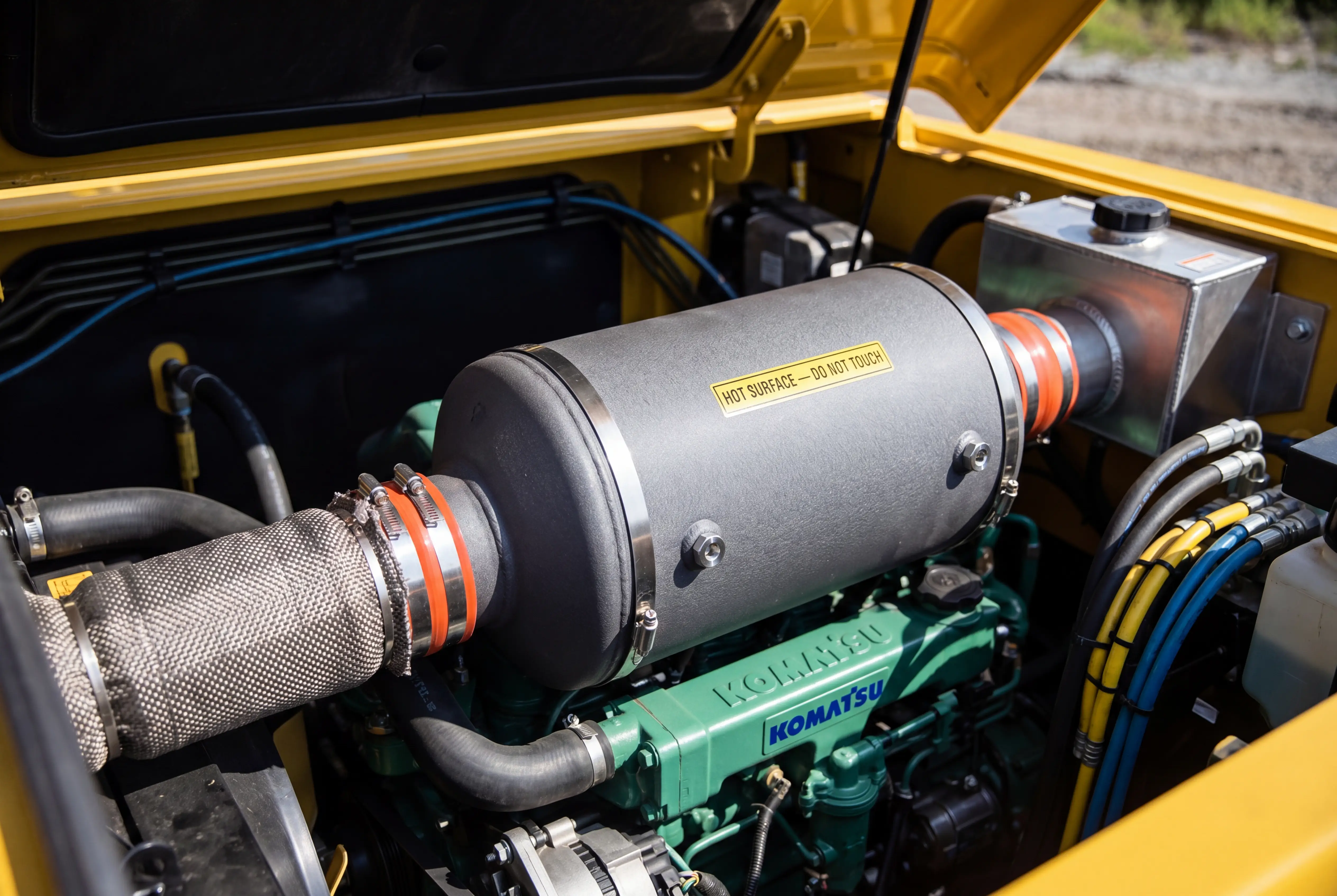 Diesel Particulate Filter DPF aftertreatment canister in excavator engine bay showing Tier 4 Final emission system components