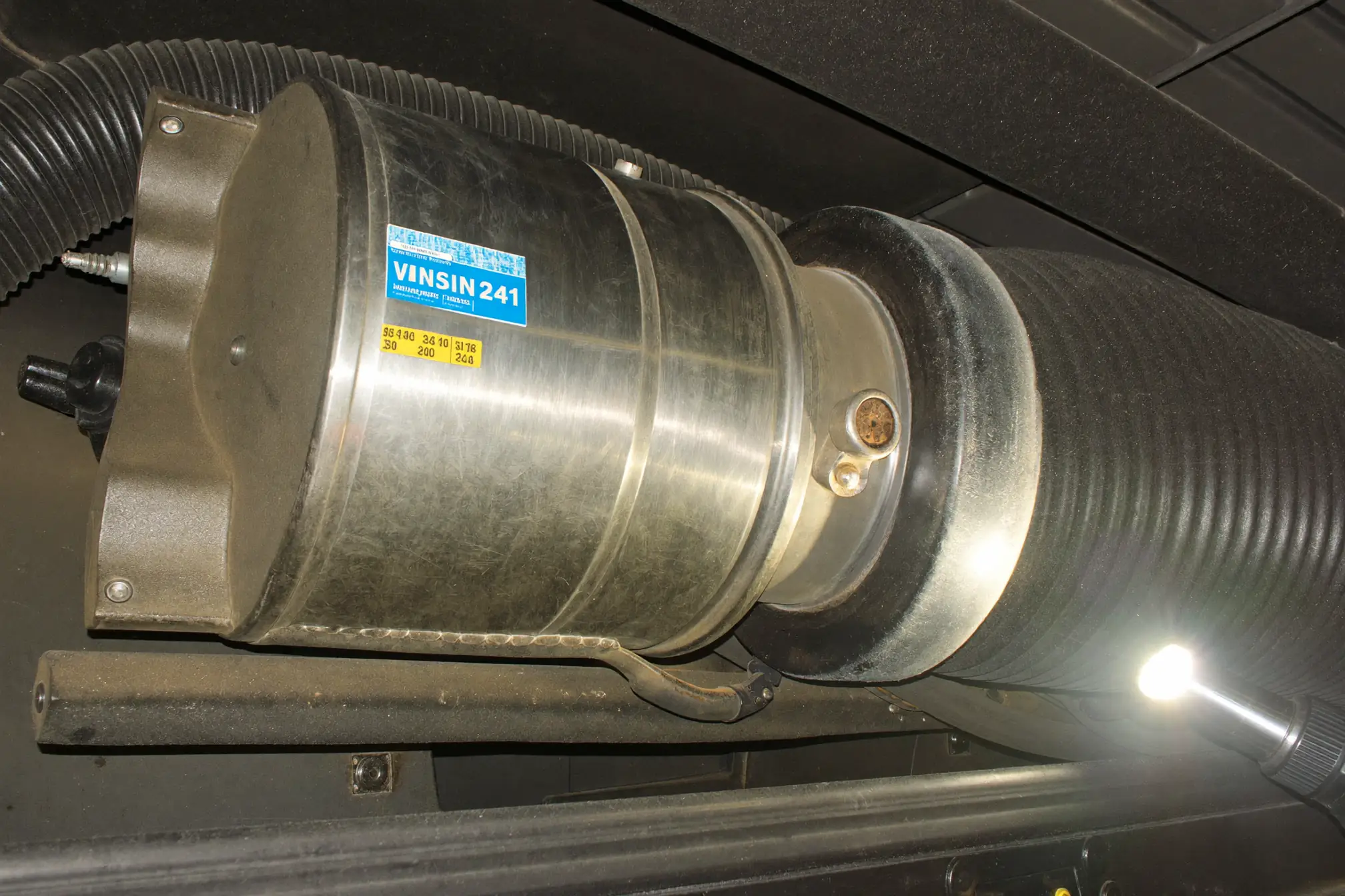 Caterpillar 349 excavator diesel particulate filter and air intake tube in service bay showing intake collar particulate indicating air leak