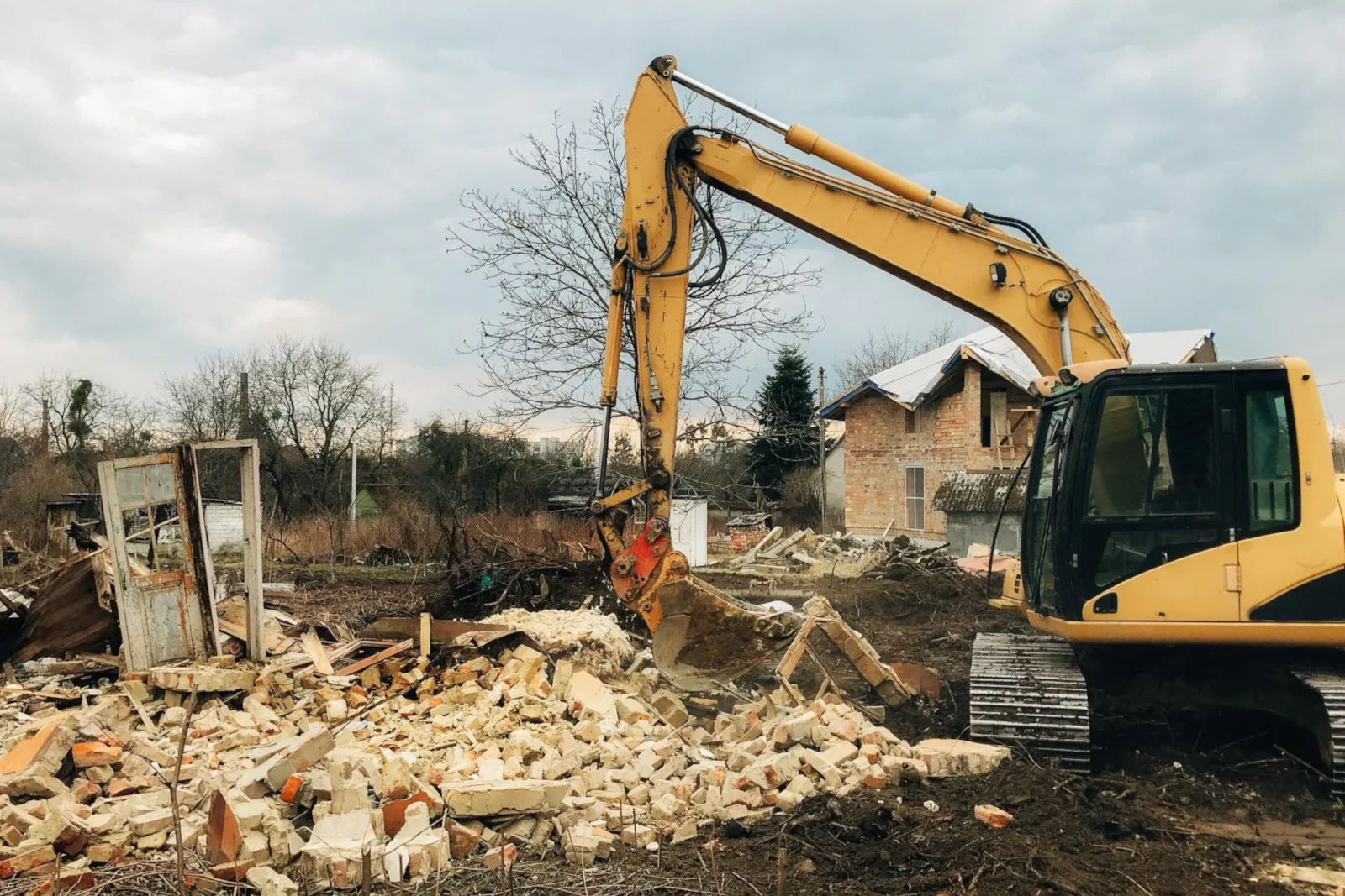 excavator destroying brick house on land in country